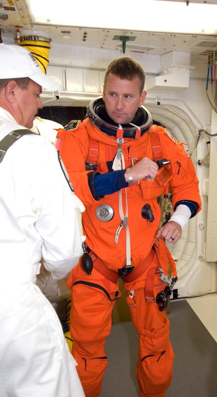 CAPE CANAVERAL, Fla. --  In the White Room on Launch Pad 39A at NASA's Kennedy Space Center, STS-124 Pilot Ken Ham secures the parachute required for launch.  He and the other crew members are taking part in a simulated launch countdown, part of the launch dress rehearsal known as the terminal countdown demonstration test. The simulation serves as a practice exercise in which both the launch team and flight crew rehearse launch day time lines and procedures. The test culminates in a simulated ignition and automated shutdown of the orbiter's main engines.  On the STS-124 mission, the crew will deliver and install the Japanese Experiment Module – Pressurized Module and Japanese Remote Manipulator System.  Discovery's launch is targeted for May 31.  Photo credit: NASA/Amanda Diller