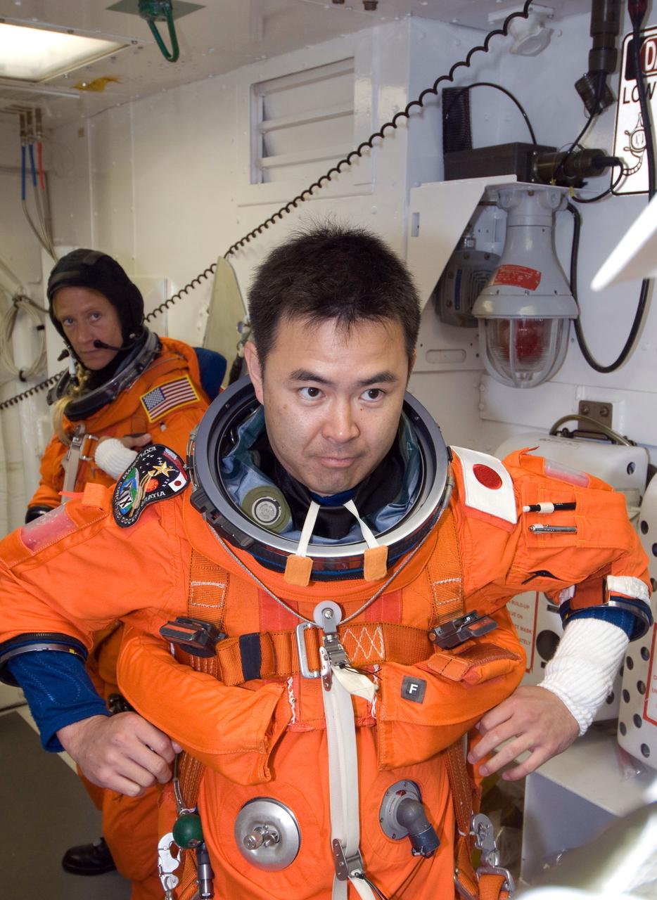 CAPE CANAVERAL, Fla. -- In the White Room on Launch Pad 39A at NASA's Kennedy Space Center, STS-124 Mission Specialist Akihiko Hoshide adjusts his parachute required for launch.  Hoshide represents the Japan Aerospace Exploration Agency.  Behind him is Mission Specialist Karen Nyberg.  They and the other crew members are taking part in a simulated launch countdown, part of the launch dress rehearsal known as the terminal countdown demonstration test. The simulation serves as a practice exercise in which both the launch team and flight crew rehearse launch day time lines and procedures. The test culminates in a simulated ignition and automated shutdown of the orbiter's main engines.  On the STS-124 mission, the crew will deliver and install the Japanese Experiment Module – Pressurized Module and Japanese Remote Manipulator System.  Discovery's launch is targeted for May 31.  Photo credit: NASA/Amanda Diller