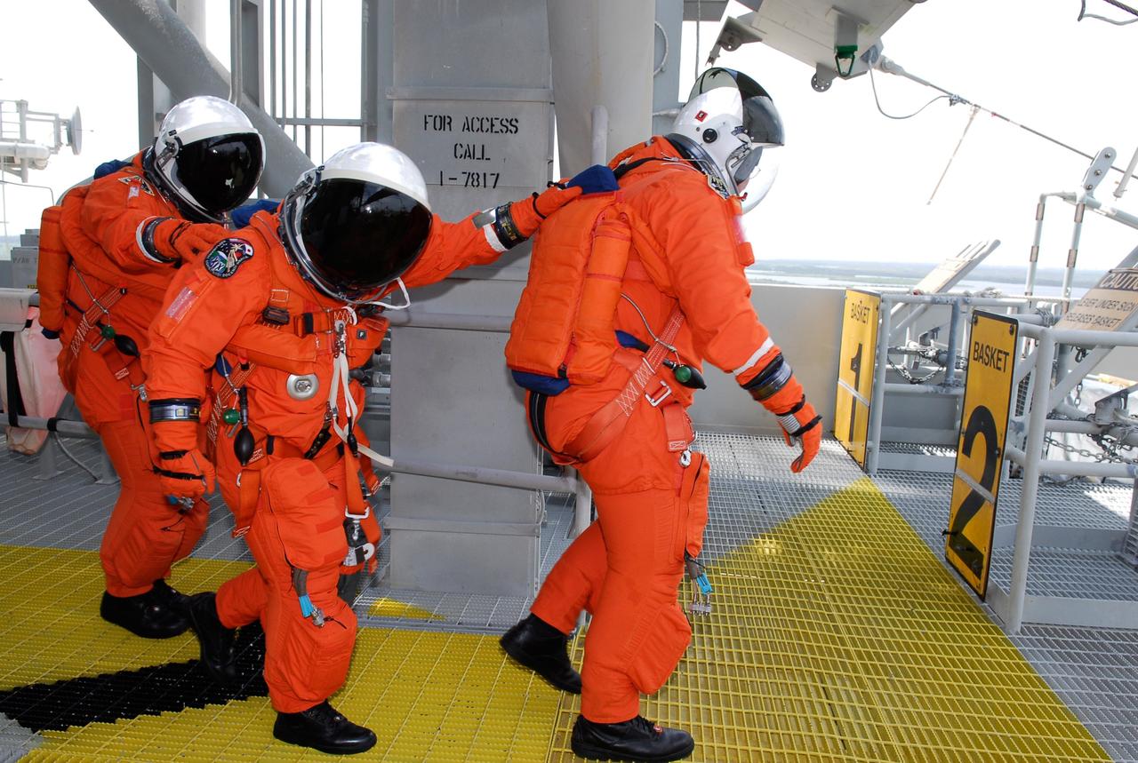 CAPE CANAVERAL, Fla. --   On Launch Pad 39A at NASA's Kennedy Space Center, STS-124 Mission Specialist Mike Fossum leads two other astronauts to the slidewire basket area after completing the simulated launch countdown, part of the launch dress rehearsal known as the terminal countdown demonstration test. The crew is practicing emergency egress from the 195-foot level of the fixed service structure. TCDT provides astronauts and ground crews with an opportunity to participate in various simulated countdown activities, including a simulated launch countdown, equipment familiarization and emergency egress training.  On the STS-124 mission, the crew will deliver and install the Japanese Experiment Module – Pressurized Module and Japanese Remote Manipulator System.  Discovery's launch is targeted for May 31.   Photo credit: NASA/Kim Shiflett