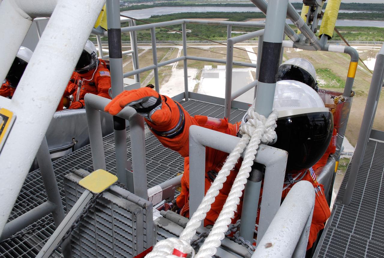 CAPE CANAVERAL, Fla. -- On Launch Pad 39A at NASA's Kennedy Space Center, STS-124 crew members climb into the slidewire baskets on the 195-foot level of the fixed service structure. The baskets are used for emergency egress, part of the launch dress rehearsal known as the terminal countdown demonstration test. TCDT provides astronauts and ground crews with an opportunity to participate in various simulated countdown activities, including a simulated launch countdown, equipment familiarization and emergency egress training. On the STS-124 mission, the crew will deliver and install the Japanese Experiment Module – Pressurized Module and Japanese Remote Manipulator System. Discovery's launch is targeted for May 31. Photo credit: NASA/Kim Shiflett