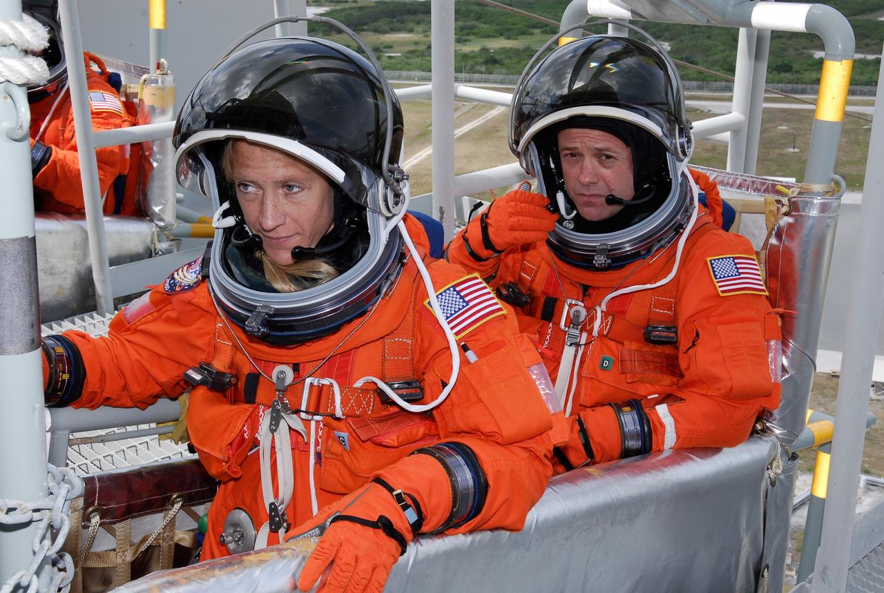 CAPE CANAVERAL, Fla. --  On Launch Pad 39A at NASA's Kennedy Space Center, STS-124 Mission Specialists Karen Nyberg (left) and Ron Garan have reached the slidewire baskets on the 195-foot level of the fixed service structure.  The baskets are used for emergency egress, part of the launch dress rehearsal known as the terminal countdown demonstration test. TCDT provides astronauts and ground crews with an opportunity to participate in various simulated countdown activities, including a simulated launch countdown, equipment familiarization and emergency egress training.  On the STS-124 mission, the crew will deliver and install the Japanese Experiment Module – Pressurized Module and Japanese Remote Manipulator System.  Discovery's launch is targeted for May 31.   Photo credit: NASA/Kim Shiflett