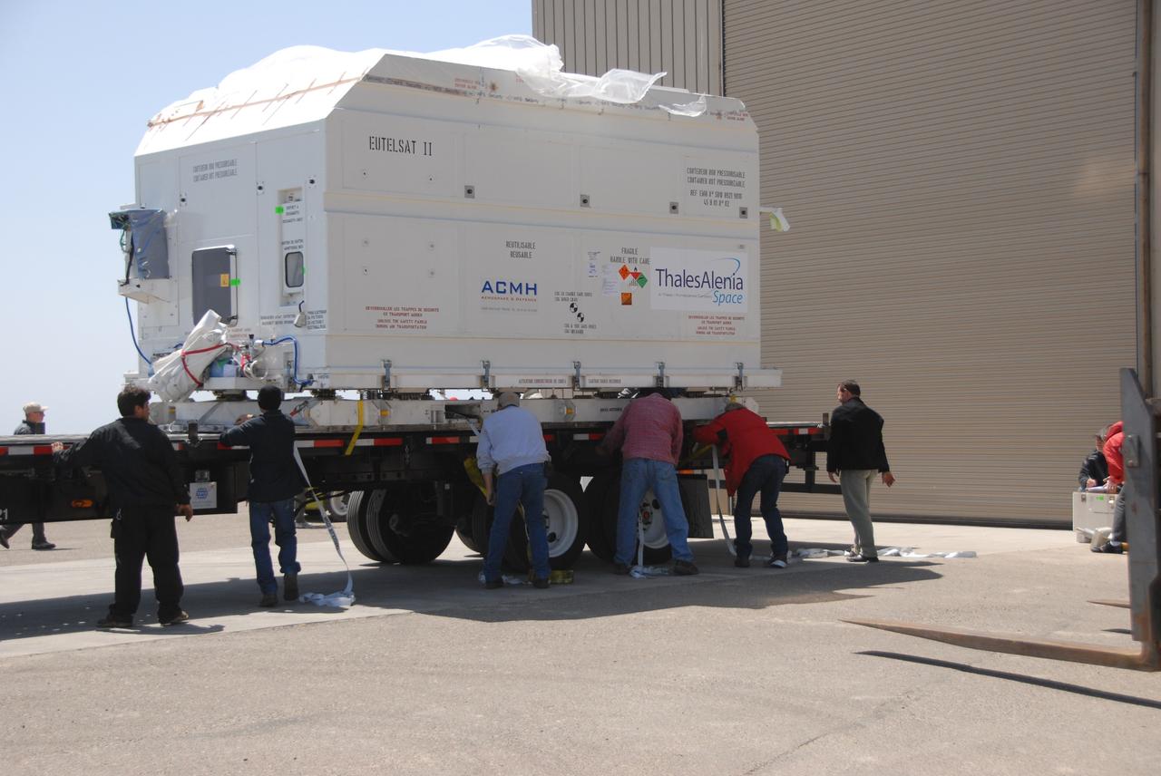VANDENBERG AIR FORCE BASE, Calif. --  At Vandenberg Air Force Base, workers remove the straps holding the OSTM/Jason-2 satellite shipping container on the flatbed truck.  The container will be moved inside the Astrotech processing facility at right.  The OSTM, or Ocean Topography Mission, on the Jason-2 satellite is a follow-on to Jason-1. It will take oceanographic studies of sea surface height into an operational mode for continued climate forecasting research and science and industrial applications.  This satellite altimetry data will help determine ocean circulation, climate change and sea-level rise. OSTM is a joint effort by the National Oceanic and Atmospheric Administration, NASA, France’s Centre National d’Etudes Spatiales and the European Meteorological Satellite Organisation. OSTM/Jason-2 will be launched aboard a United Launch Alliance Delta II 7320 from Vandenberg on June 15.  Photo credit: NASA/Dan Liberotti