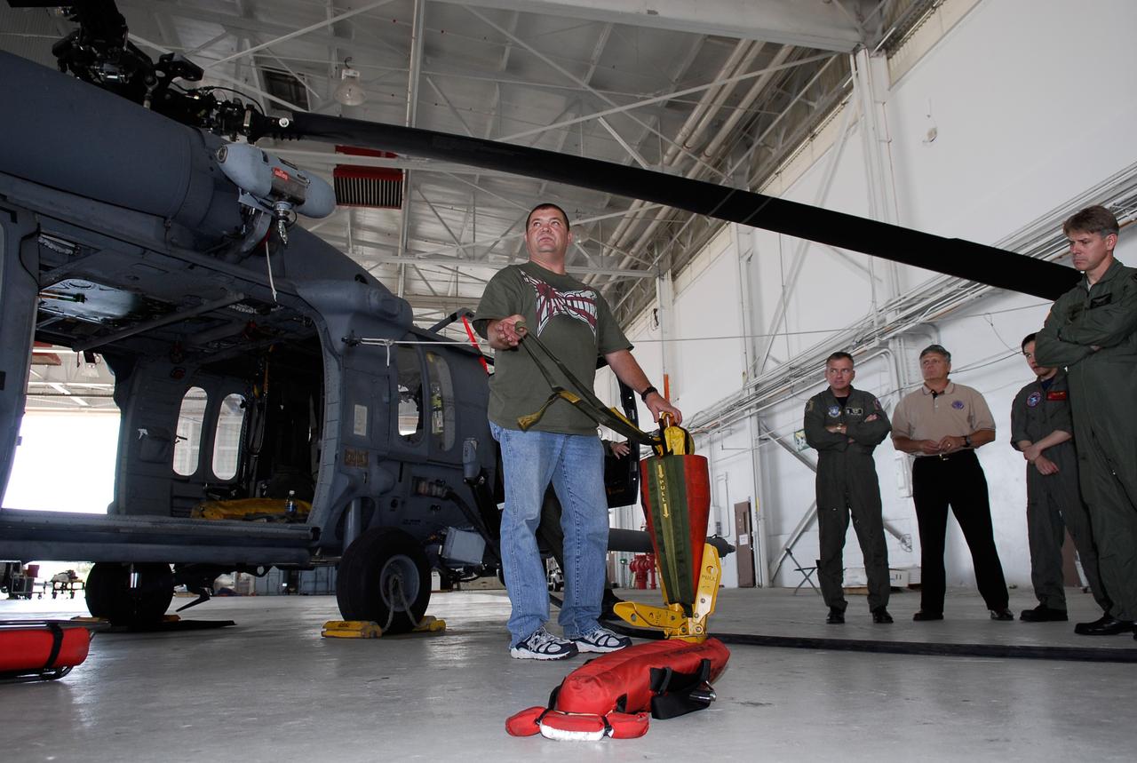 CAPE CANAVERAL, Fla. -- A representative of the 301st Rescue Squadron demonstrates rescue equipment that is used by participants in the Mode VIII exercise being conducted at Patrick Air Force Base, Fla. In the background is an HH-60G helicopter. In support of, and with logistical support from, NASA, USSTRATCOM is hosting a major exercise involving Department of Defense, Department of Homeland Security, search and rescue (SAR) forces, including the 45th Space Wing at Patrick Air Force Base, which support space shuttle astronaut bailout contingency operations, known as Mode VIII. This exercise tests SAR capabilities to locate, recover and provide medical treatment for astronauts following a space shuttle launch phase open-ocean bailout. Participants include members of the U.S. Navy, U.S. Coast Guard, U.S. Air Force, and NASA's Kennedy Space Center and Johnson Space Center. This will be the 15th Mode VIII exercise conducted in the past 20 years. Photo credit: NASA/Kim Shiflett