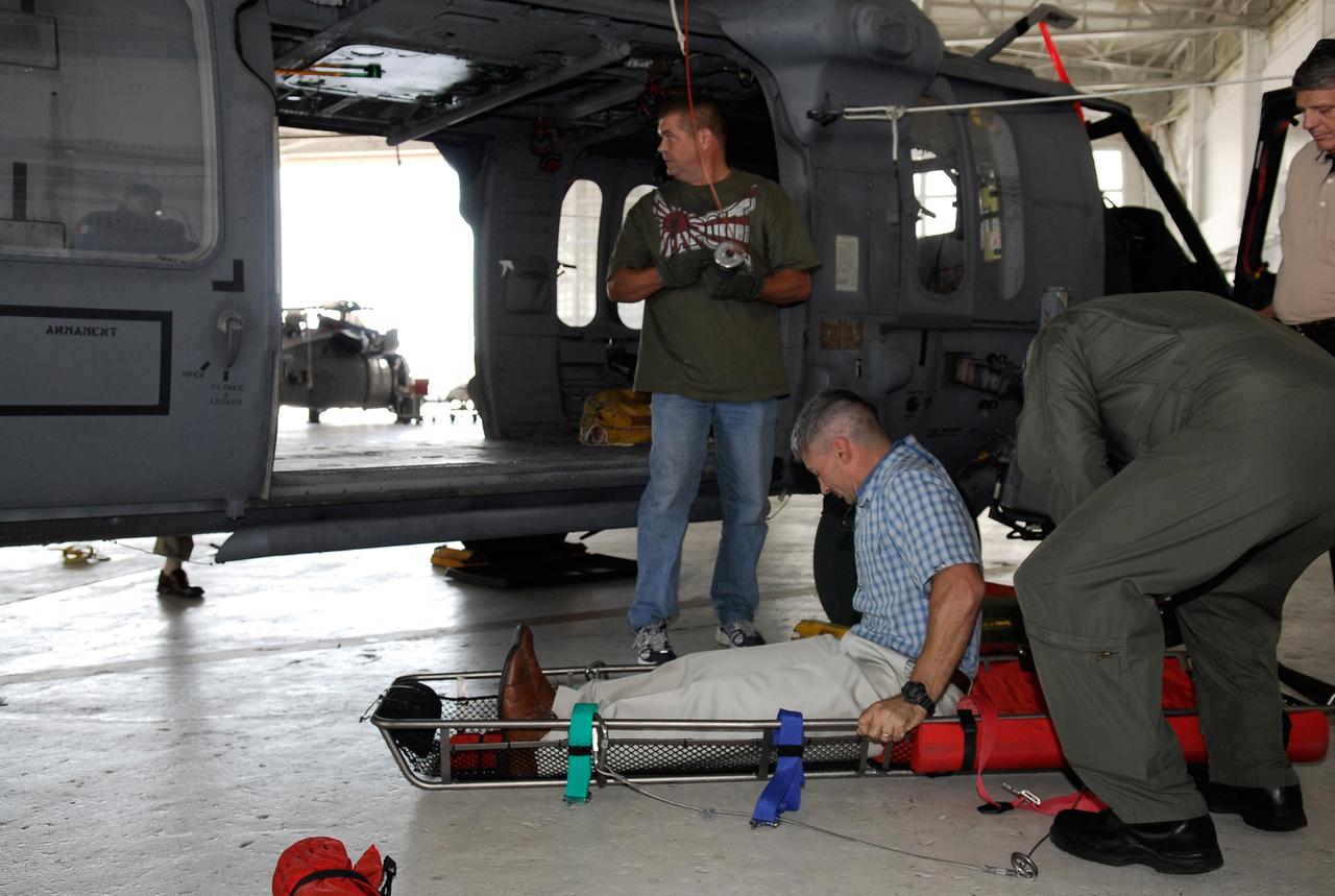 CAPE CANAVERAL, Fla. -- A representative of the 301st Rescue Squadron and a volunteer from the NASA Vehicle Integration Test Team office get ready to demonstrate rescue equipment that is used by participants in the Mode VIII exercise being conducted at Patrick Air Force Base. In the background is an HH-60G helicopter. In support of, and with logistical support from, NASA, USSTRATCOM is hosting a major exercise involving Department of Defense, Department of Homeland Security, search and rescue (SAR) forces, including the 45th Space Wing at Patrick Air Force Base, which support space shuttle astronaut bailout contingency operations, known as Mode VIII. This exercise tests SAR capabilities to locate, recover and provide medical treatment for astronauts following a space shuttle launch phase open-ocean bailout. Participants include members of the U.S. Navy, U.S. Coast Guard, U.S. Air Force, and NASA's Kennedy Space Center and Johnson Space Center. This will be the 15th Mode VIII exercise conducted in the past 20 years. Photo credit: NASA/Kim Shiflett
