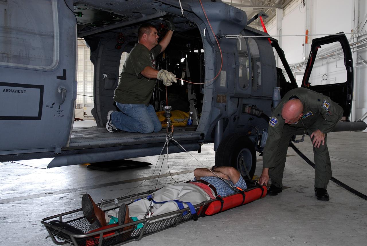 CAPE CANAVERAL, Fla. -- A representative of the 301st Rescue Squadron and a volunteer (in the stretcher) from the NASA Vehicle Integration Test Team office get ready to demonstrate rescue equipment on the HH-60G helicopter that is used by participants in the Mode VIII exercise being conducted at Patrick Air Force Base, Fla. In support of, and with logistical support from, NASA, USSTRATCOM is hosting a major exercise involving Department of Defense, Department of Homeland Security, search and rescue (SAR) forces, including the 45th Space Wing at Patrick Air Force Base, which support space shuttle astronaut bailout contingency operations, known as Mode VIII. This exercise tests SAR capabilities to locate, recover and provide medical treatment for astronauts following a space shuttle launch phase open-ocean bailout. Participants include members of the U.S. Navy, U.S. Coast Guard, U.S. Air Force, and NASA's Kennedy Space Center and Johnson Space Center. This will be the 15th Mode VIII exercise conducted in the past 20 years. Photo credit: NASA/Kim Shiflett