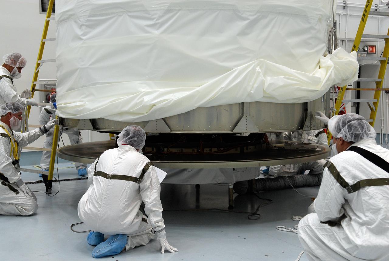CAPE CANAVERAL, Fla. --  At Astrotech in Titusville, Fla., technicians check the alignment of the payload transportation canister as it is lowered over the GLAST spacecraft for installation. The spacecraft will be moved to pad 17-B at Cape Canaveral Air Force Station.  At the pad, NASA's Gamma-Ray Large Area Space Telescope will be lifted into the mobile service tower and encapsulated in the fairing for launch.  GLAST  is a powerful space observatory that will explore the Universe's ultimate frontier, where nature harnesses forces and energies far beyond anything possible on Earth;  probe some of science's deepest questions, such as what our Universe is made of, and search for new laws of physics; explain how black holes accelerate jets of material to nearly light speed; and help crack the mystery of stupendously powerful explosions known as gamma-ray bursts. The launch date is targeted no earlier than June 3.   Photo credit: NASA/Kim Shiflett