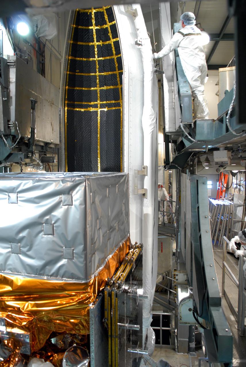 CAPE CANAVERAL, Fla. --  Inside the mobile service tower on Launch Pad 17-B at Cape Canaveral Air Force Station, workers help guide one section of the payload fairing into place around NASA's Gamma-Ray Large Area Space Telescope, or GLAST.  The fairing is a molded structure that fits flush with the outside surface of the Delta II upper stage booster and forms an aerodynamically smooth nose cone, protecting the spacecraft during launch and ascent. GLAST  is a powerful space observatory that will explore the Universe's ultimate frontier, where nature harnesses forces and energies far beyond anything possible on Earth;  probe some of science's deepest questions, such as what our Universe is made of, and search for new laws of physics; explain how black holes accelerate jets of material to nearly light speed; and help crack the mystery of stupendously powerful explosions known as gamma-ray bursts. The launch date is targeted no earlier than June 3. Photo credit: NASA/Jim Grossmann