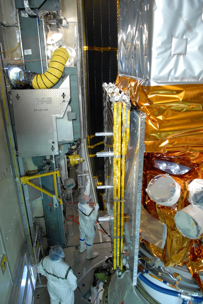 CAPE CANAVERAL, Fla. --  Inside the mobile service tower on Launch Pad 17-B at Cape Canaveral Air Force Station, workers help guide one section of the payload fairing into place around NASA's Gamma-Ray Large Area Space Telescope, or GLAST. The fairing is a molded structure that fits flush with the outside surface of the Delta II upper stage booster and forms an aerodynamically smooth nose cone, protecting the spacecraft during launch and ascent. GLAST  is a powerful space observatory that will explore the Universe's ultimate frontier, where nature harnesses forces and energies far beyond anything possible on Earth;  probe some of science's deepest questions, such as what our Universe is made of, and search for new laws of physics; explain how black holes accelerate jets of material to nearly light speed; and help crack the mystery of stupendously powerful explosions known as gamma-ray bursts. The launch date is targeted no earlier than June 3. Photo credit: NASA/Jim Grossmann
