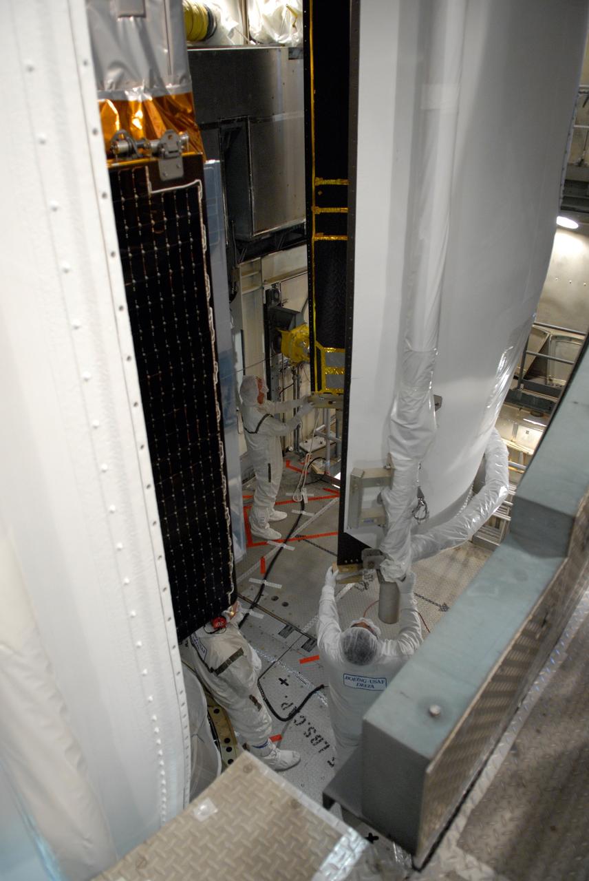 CAPE CANAVERAL, Fla. --   Inside the mobile service tower on Launch Pad 17-B at Cape Canaveral Air Force Station, workers help guide the second section of the payload fairing into place around NASA's Gamma-Ray Large Area Space Telescope, or GLAST.  The first half is seen at left.  The fairing is a molded structure that fits flush with the outside surface of the Delta II upper stage booster and forms an aerodynamically smooth nose cone, protecting the spacecraft during launch and ascent. GLAST  is a powerful space observatory that will explore the Universe's ultimate frontier, where nature harnesses forces and energies far beyond anything possible on Earth;  probe some of science's deepest questions, such as what our Universe is made of, and search for new laws of physics; explain how black holes accelerate jets of material to nearly light speed; and help crack the mystery of stupendously powerful explosions known as gamma-ray bursts. The launch date is targeted no earlier than June 3. Photo credit: NASA/Jim Grossmann