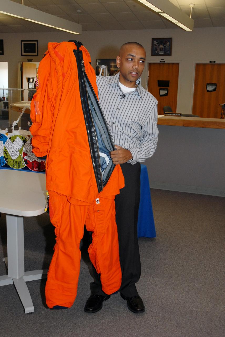 CAPE CANAVERAL, Fla. --    In the NASA News Center at NASA's Kennedy Space Center, Shuttle Crew Escape System Manager KC Chhipwadia demonstrates the launch and entry suit used by shuttle crews during their missions.  He explains that entry into the suit is from the back.  Photo credit:  NASA/Amanda Diller