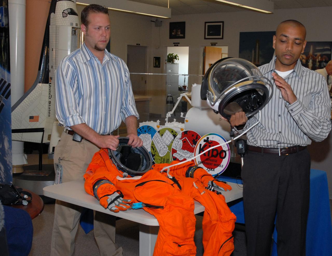 CAPE CANAVERAL, Fla. --  In the NASA News Center at NASA's Kennedy Space Center, Shuttle Crew Escape System Manager KC Chhipwadia (right) describes for the media the elements of the helmet that is part of the launch and entry suit (seen on the table) used by shuttle crews during their missions.  The helmet provides oxygen when needed plus a communication system.   Photo credit:  NASA/Amanda Diller