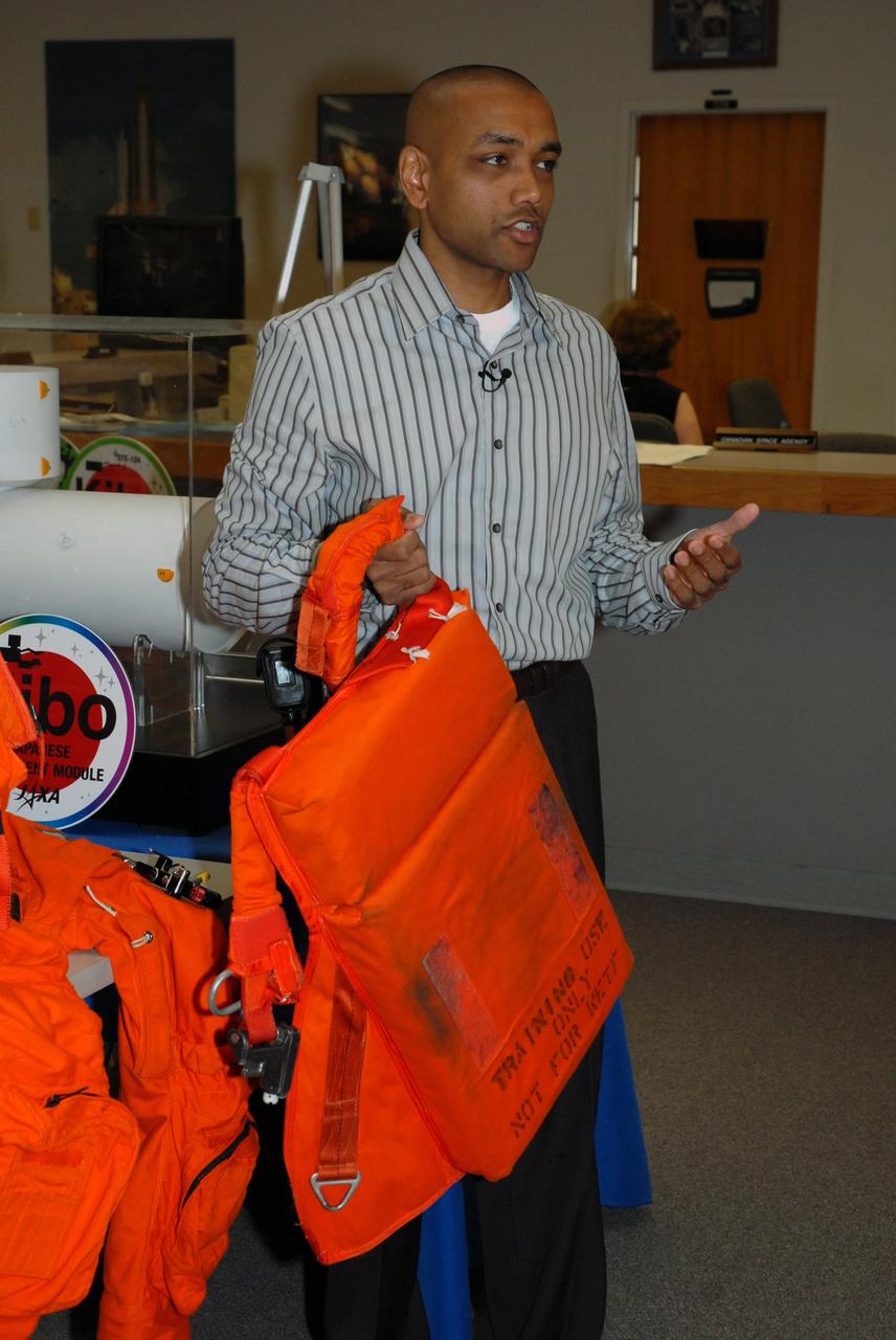 CAPE CANAVERAL, Fla. --  In the NASA News Center at NASA's Kennedy Space Center, Shuttle Crew Escape System Manager KC Chhipwadia describes for the media the components of the parachute worn by shuttle crews during launch and landing.  On top is a pilot and drag chute.  In the middle is the main chute.  At bottom is a survival life raft.  The elements of the suit and parachute provide safety elements in the event of an emergency.   Photo credit:  NASA/Amanda Diller