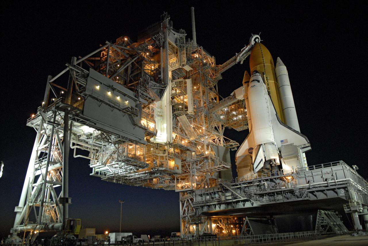 CAPE CANAVERAL, Fla. -- On Launch Pad 39A at NASA's Kennedy Space Center, the rotating service structure, or RSS, has rolled back on its axis to uncover space shuttle Discovery, lighted against the night sky, in preparation for launch on the STS-124 mission. Support for the outer end of the bridge is provided by two eight-wheel, motor-driven trucks (one is seen at bottom left) that move along circular twin rails installed flush with the pad surface. First motion was at 8:33 p.m. and rollback was complete at 9:07 p.m. The structure provides protected access to the shuttle for changeout and servicing of payloads at the pad. It is supported by a rotating bridge that pivots on a vertical axis on the west side of the pad's flame trench. After the RSS is rolled back, the orbiter is ready for fuel cell activation and external tank cryogenic propellant loading operations. The pad is cleared to the perimeter gate for operations to fill the external tank with about 500,000 gallons of cryogenic propellants used by the shuttle’s main engines. This is done at the pad approximately eight hours before the scheduled launch. Above the orange external tank is the oxygen vent hood, called the "beanie cap," at the end of the gaseous oxygen vent arm extending from the fixed service structure. Vapors are created as the liquid oxygen in the external tank boil off. The hood vents the gaseous oxygen vapors away from the space shuttle vehicle. Below is the orbiter access arm with the White Room at the end, flush against the shuttle. The White Room provides access into the shuttle. The STS-124 mission is the second of three flights launching components to complete the Japan Aerospace Exploration Agency's Kibo laboratory. The shuttle crew will install Kibo's large Japanese Pressurized Module and its remote manipulator system, or RMS. The 14-day flight includes three spacewalks. Launch is scheduled for 5:02 p.m. May 31. Photo credit: NASA/Troy Cryder