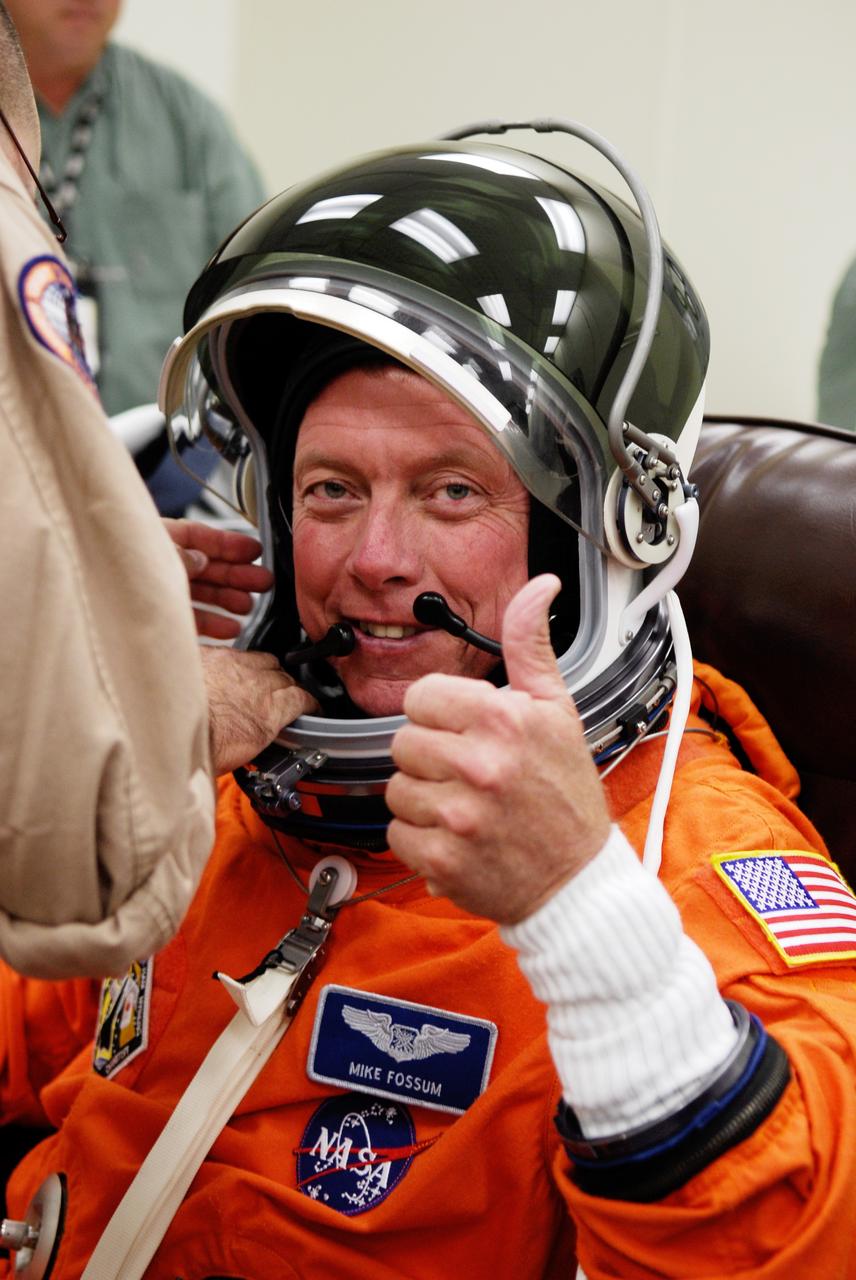 CAPE CANAVERAL, Fla. -- Crew members for space shuttle Discovery's STS-124 mission don their launch and entry suits before heading to Launch Pad 39A. Mission Specialist Mike Fossum signals he is ready for liftoff as he gets help with his helmet. The STS-124 mission is the second of three flights launching components to complete the Japan Aerospace Exploration Agency's Kibo laboratory. The shuttle crew will install Kibo's large Japanese Pressurized Module and its remote manipulator system, or RMS. The 14-day flight includes three spacewalks. Launch is scheduled for 5:02 p.m. May 31. Photo credit: NASA/Kim Shiflett