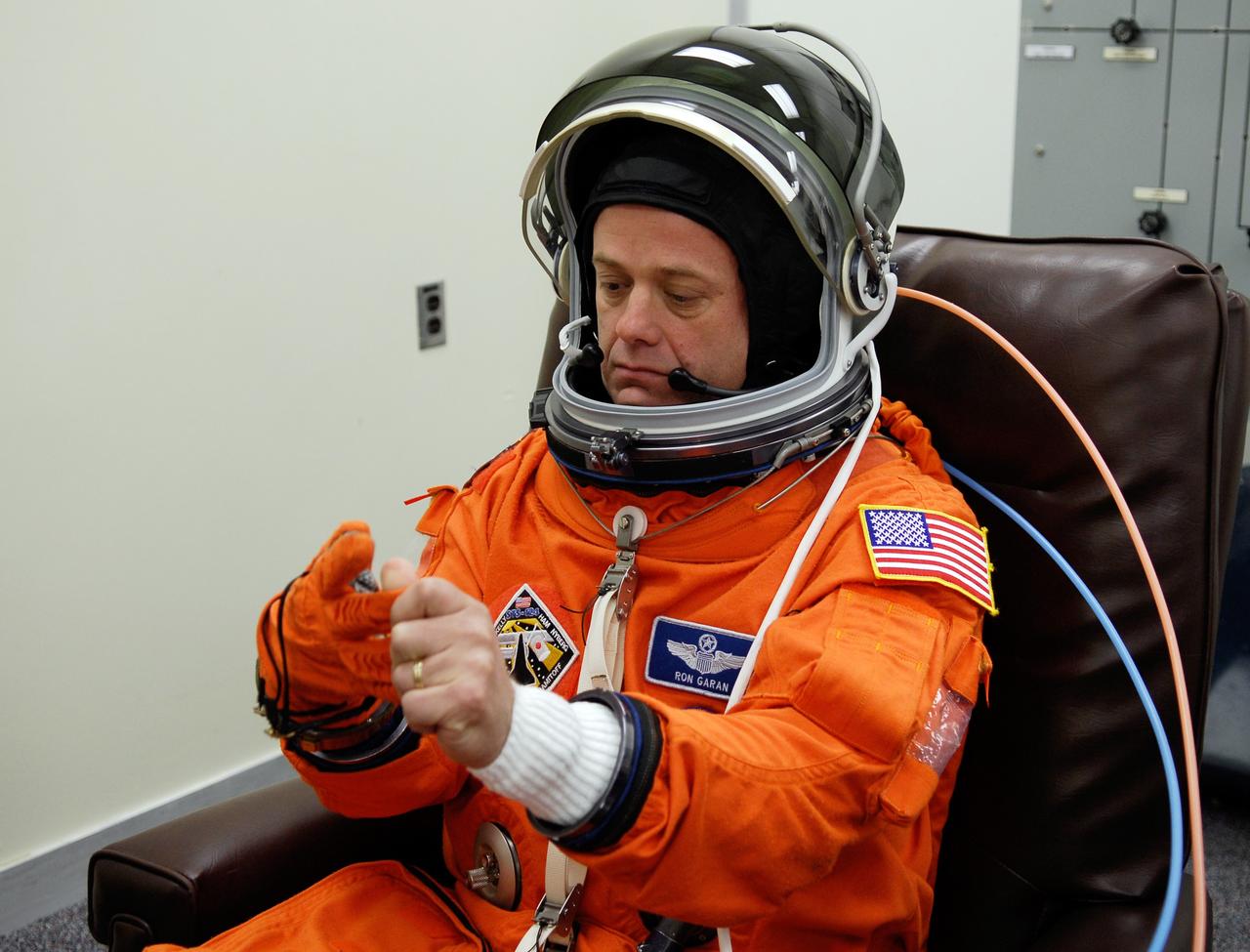 CAPE CANAVERAL, Fla. -- Crew members for space shuttle Discovery's STS-124 mission don their launch and entry suits before heading to Launch Pad 39A. Mission Specialist Ron Garan works on his glove. The STS-124 mission is the second of three flights launching components to complete the Japan Aerospace Exploration Agency's Kibo laboratory. The shuttle crew will install Kibo's large Japanese Pressurized Module and its remote manipulator system, or RMS. The 14-day flight includes three spacewalks. Launch is scheduled for 5:02 p.m. May 31. Photo credit: NASA/Kim Shiflett