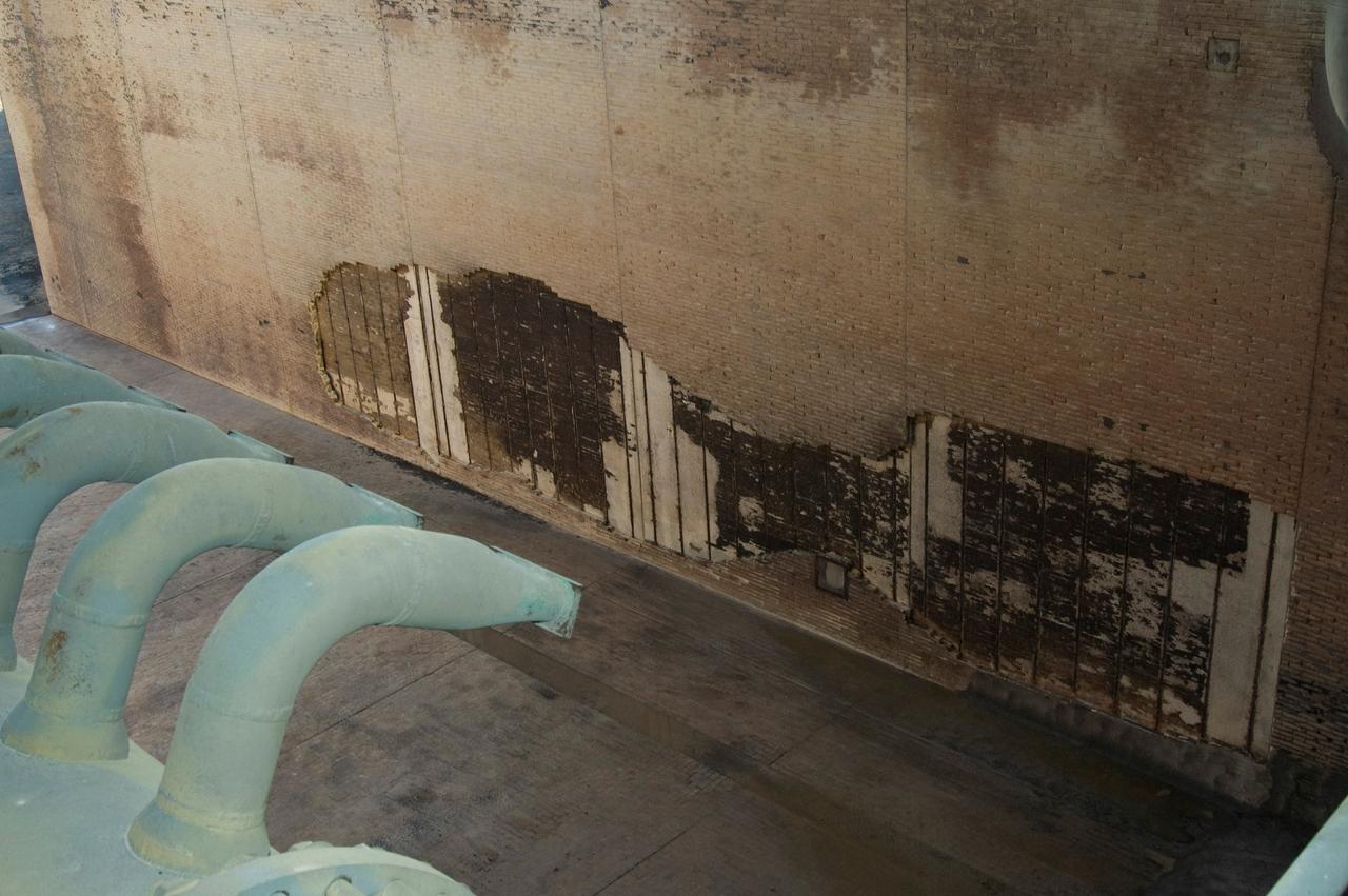 CAPE CANAVERAL, Fla. --  During the post-launch walk down of Launch Pad 39A at NASA's Kennedy Space Center, observers noted severe launch damage on a 100’ X 20’ section of the east wall of the north flame trench (seen here).  Broken sections of the flame trench wall were scattered from the flame trench to the pad perimeter fence. NASA is forming an investigation board. The flame trench transecting the pad's mound at ground level is 490 feet long, 58 feet wide and 40 feet high. It is made of concrete and refractory brick.  The top of the solid rocket booster flame deflector abuts with that of the orbiter flame deflector to form a flattened, inverted V-shaped structure beneath the mobile launcher platform's three exhaust holes. The orbiter flame deflector is fixed and is 38 feet high, 72 feet long and 57.6 feet wide. The deflector weighs 1.3 million pounds.  The solid rocket booster deflector is 42.5 feet high, 42 feet long and 57 feet wide. The structure weighs 1.1 million pounds.  The deflectors are built of steel and covered with a high-temperature concrete surface with an average thickness of 5 inches. There are two movable solid rocket booster side flame deflectors, one located on each side of the flame trench. They are 19.5 feet high, 44 feet long and 17.5 feet wide.  Photo credit: NASA/Jim Grossmann