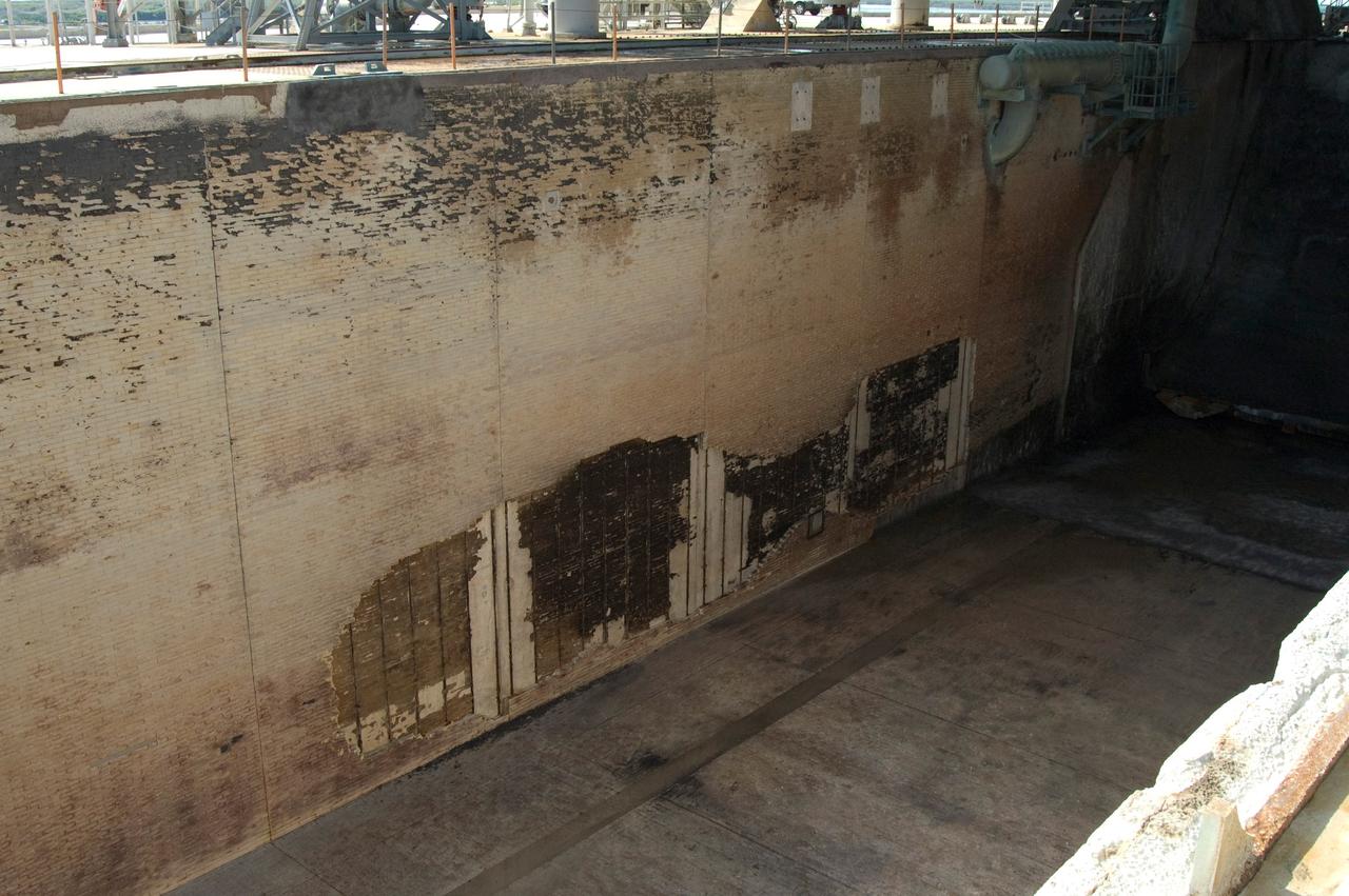 CAPE CANAVERAL, Fla. --  During the post-launch walk down of Launch Pad 39A at NASA's Kennedy Space Center, the pad team noted severe launch damage on a 100’ X 20’ section of the east wall of the north flame trench (seen here).  Broken sections of the flame trench wall were scattered from the flame trench to the pad perimeter fence. NASA is forming an investigation board. The flame trench transecting the pad's mound at ground level is 490 feet long, 58 feet wide and 40 feet high. It is made of concrete and refractory brick.  The top of the solid rocket booster flame deflector abuts with that of the orbiter flame deflector to form a flattened, inverted V-shaped structure beneath the mobile launcher platform's three exhaust holes. The orbiter flame deflector is fixed and is 38 feet high, 72 feet long and 57.6 feet wide. The deflector weighs 1.3 million pounds.  The solid rocket booster deflector is 42.5 feet high, 42 feet long and 57 feet wide. The structure weighs 1.1 million pounds.  The deflectors are built of steel and covered with a high-temperature concrete surface with an average thickness of 5 inches. There are two movable solid rocket booster side flame deflectors, one located on each side of the flame trench. They are 19.5 feet high, 44 feet long and 17.5 feet wide.  Photo credit: NASA/Jim Grossmann