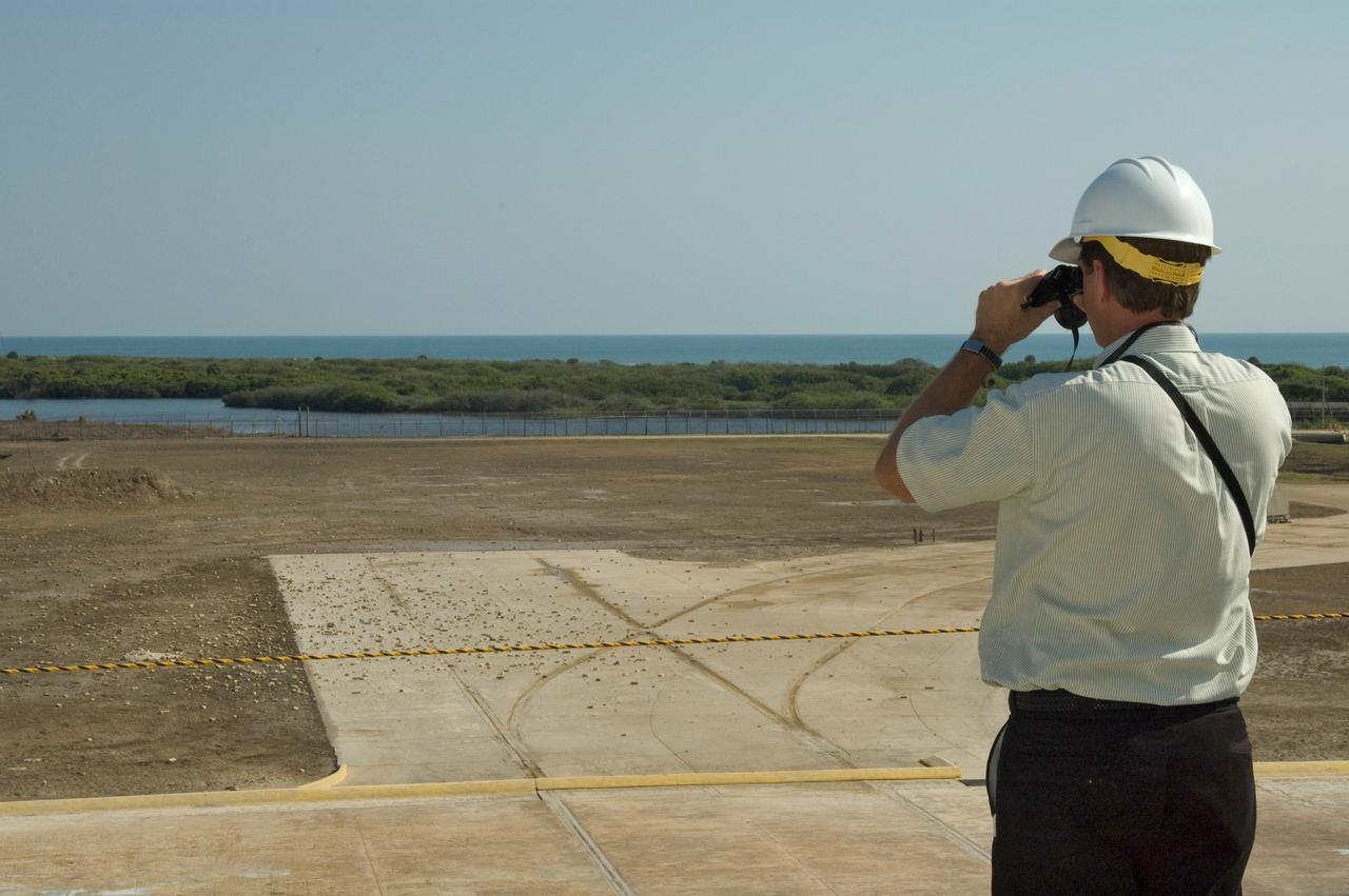 CAPE CANAVERAL, Fla. --  A member of the walk-down team takes a close look at debris scattered across Launch Pad 39A at NASA's Kennedy Space Center following launch of space shuttle Discovery on its STS-124 mission.  During the post-launch walk down, the pad team noted severe launch damage on a 100’ X 20’ section of the east wall of the north flame trench. Broken sections of the flame trench wall were scattered from the flame trench to the pad perimeter fence. NASA is forming an investigation board. The flame trench transecting the pad's mound at ground level is 490 feet long, 58 feet wide and 40 feet high. It is made of concrete and refractory brick.  The top of the solid rocket booster flame deflector abuts with that of the orbiter flame deflector to form a flattened, inverted V-shaped structure beneath the mobile launcher platform's three exhaust holes. The orbiter flame deflector is fixed and is 38 feet high, 72 feet long and 57.6 feet wide. The deflector weighs 1.3 million pounds.  The solid rocket booster deflector is 42.5 feet high, 42 feet long and 57 feet wide. The structure weighs 1.1 million pounds.  The deflectors are built of steel and covered with a high-temperature concrete surface with an average thickness of 5 inches. There are two movable solid rocket booster side flame deflectors, one located on each side of the flame trench. They are 19.5 feet high, 44 feet long and 17.5 feet wide.  Photo credit: NASA/Jim Grossmann