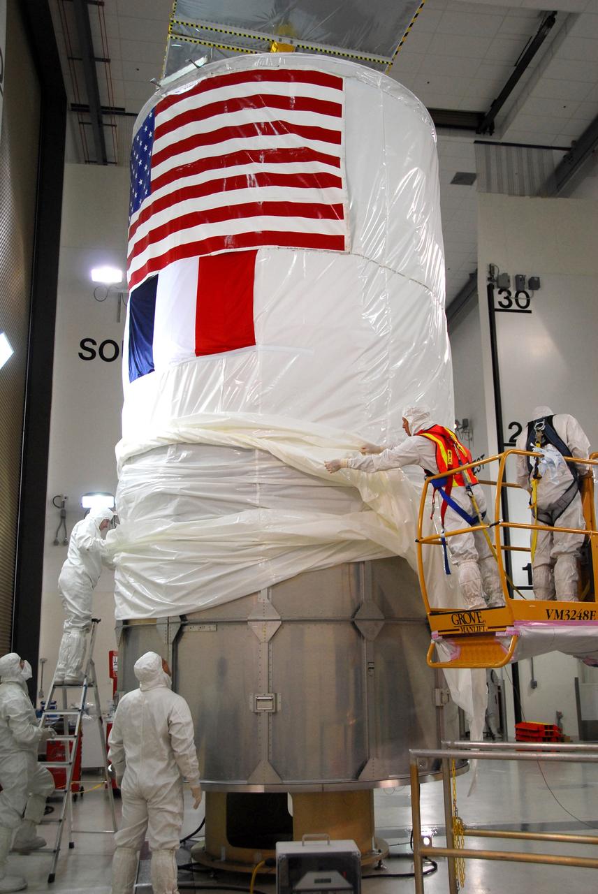 VANDENBERG AIR FORCE BASE, Calif. – Workers pull the protective cover from the upper canister over the lower segments surrounding the Ocean Surface Topography Mission, or OSTM/Jason 2, spacecraft. The OSTM/Jason 2 will be transported to the launch pad. The launch of the OSTM/Jason 2 aboard a Delta II rocket is scheduled for Friday, June 20, from Vandenberg Air Force Base in California. The launch window extends from 12:46 a.m. to 12:55 a.m. PDT. The satellite will be placed in an 830-mile-high orbit at an inclination of 66 degrees after separating from the Delta II 55 minutes after liftoff. The five primary science instruments of the Ocean Surface Topography Mission aboard the Jason 2 spacecraft are dedicated to measuring ocean surface height. These measurements will be used to evaluate and forecast climate changes and improve weather forecasting. The results also are expected to help forecasters better predict hurricane intensity. Photo credit: NASA/Dan Liberotti