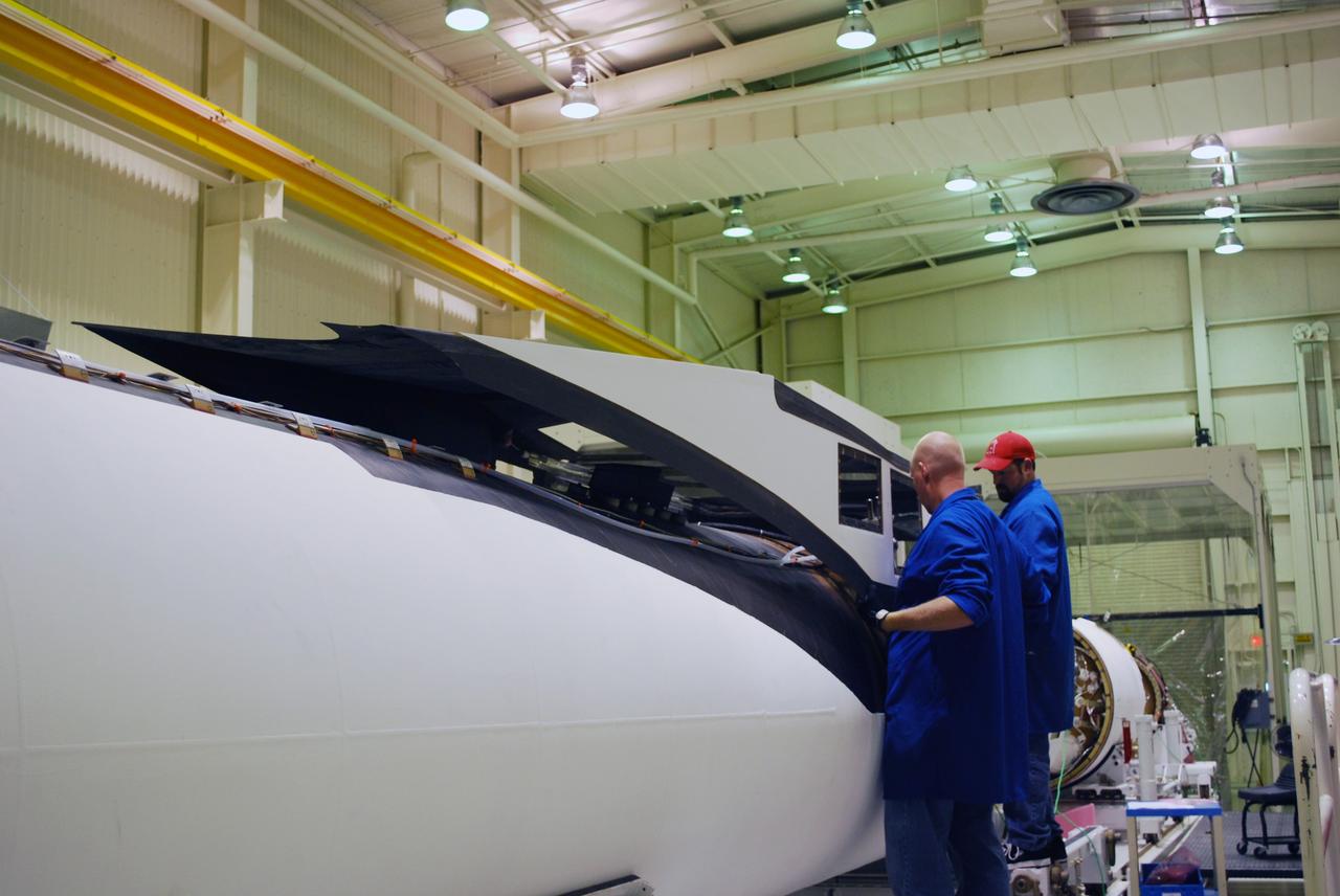 VANDENBERG AIR FORCE BASE, Calif. – In Building 1555, workers help guide the fillet into place on the Pegasus XL launch vehicle. The Pegasus will launch NASA's Interstellar Boundary Explorer Mission, or IBEX, satellite from Kwajalein Island in the Marshall Islands, South Pacific. IBEX will make the first map of the boundary between the solar system and interstellar space. IBEX is the first mission designed to detect the edge of the solar system. As the solar wind from the sun flows out beyond Pluto, it collides with the material between the stars, forming a shock front. IBEX contains two neutral atom imagers designed to detect particles from the termination shock at the boundary between the solar system and interstellar space. IBEX also will study galactic cosmic rays, energetic particles from beyond the solar system that pose a health and safety hazard for humans exploring beyond Earth orbit. IBEX will make these observations from a highly elliptical orbit that takes it beyond the interference of the Earth's magnetosphere. Photo credit: NASA/Randy Beaudoin