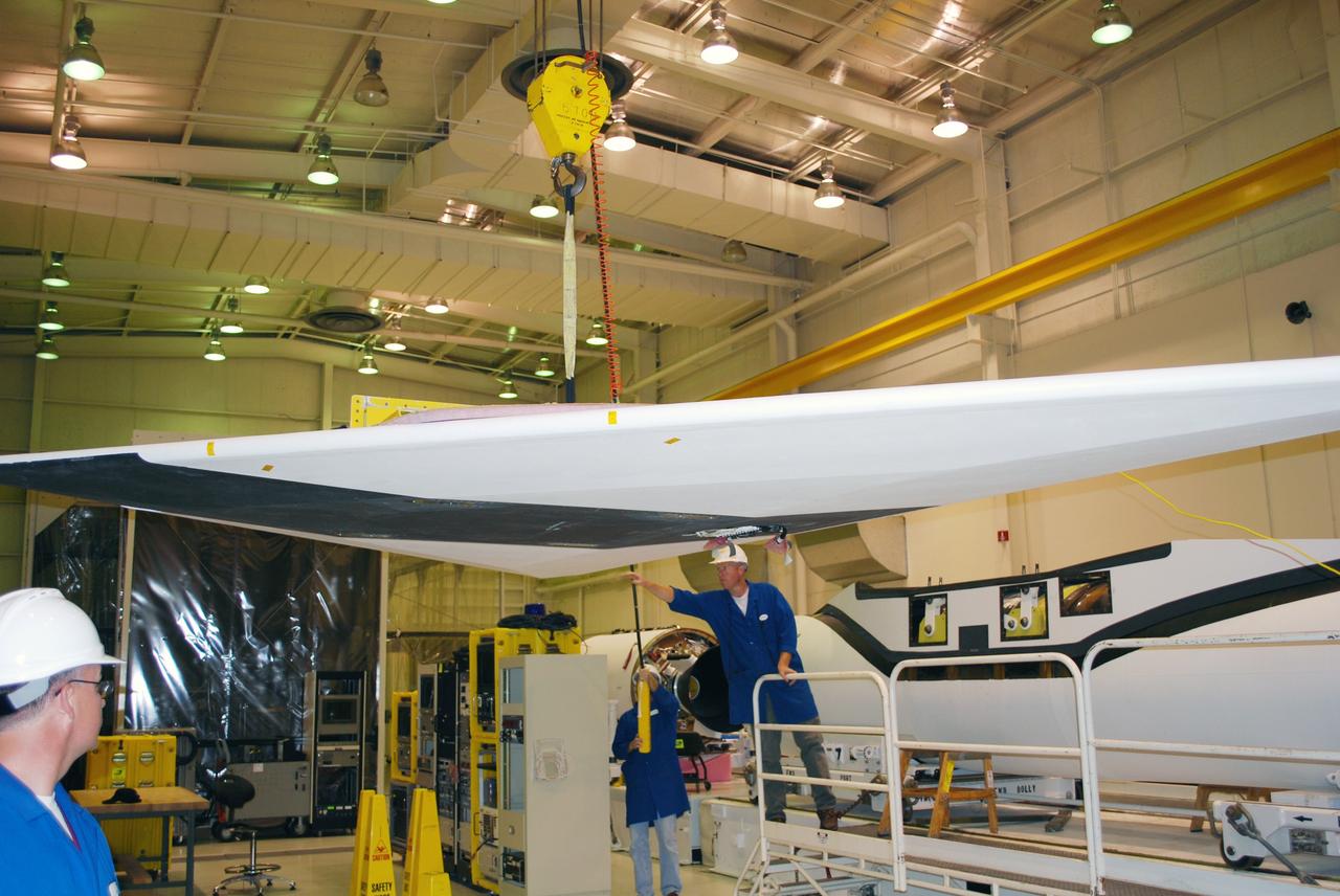 VANDENBERG AIR FORCE BASE, Calif. – In Building 1555, workers help guide a wing toward the Pegasus XL launch vehicle in the background for a fit check. The Pegasus will launch NASA's Interstellar Boundary Explorer Mission, or IBEX, satellite from Kwajalein Island in the Marshall Islands, South Pacific. IBEX will make the first map of the boundary between the solar system and interstellar space. IBEX is the first mission designed to detect the edge of the solar system. As the solar wind from the sun flows out beyond Pluto, it collides with the material between the stars, forming a shock front. IBEX contains two neutral atom imagers designed to detect particles from the termination shock at the boundary between the solar system and interstellar space. IBEX also will study galactic cosmic rays, energetic particles from beyond the solar system that pose a health and safety hazard for humans exploring beyond Earth orbit. IBEX will make these observations from a highly elliptical orbit that takes it beyond the interference of the Earth's magnetosphere. Photo credit: NASA/Randy Beaudoin