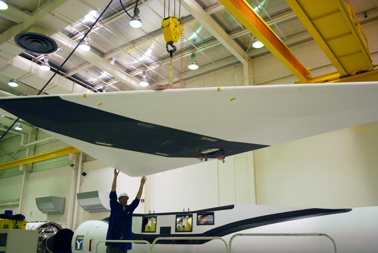 VANDENBERG AIR FORCE BASE, Calif. – In Building 1555, workers help guide a wing toward the Pegasus XL launch vehicle in the background for a fit check. The Pegasus will launch NASA's Interstellar Boundary Explorer Mission, or IBEX, satellite from Kwajalein Island in the Marshall Islands, South Pacific. IBEX will make the first map of the boundary between the solar system and interstellar space. IBEX is the first mission designed to detect the edge of the solar system. As the solar wind from the sun flows out beyond Pluto, it collides with the material between the stars, forming a shock front. IBEX contains two neutral atom imagers designed to detect particles from the termination shock at the boundary between the solar system and interstellar space. IBEX also will study galactic cosmic rays, energetic particles from beyond the solar system that pose a health and safety hazard for humans exploring beyond Earth orbit. IBEX will make these observations from a highly elliptical orbit that takes it beyond the interference of the Earth's magnetosphere. Photo credit: NASA/Randy Beaudoin