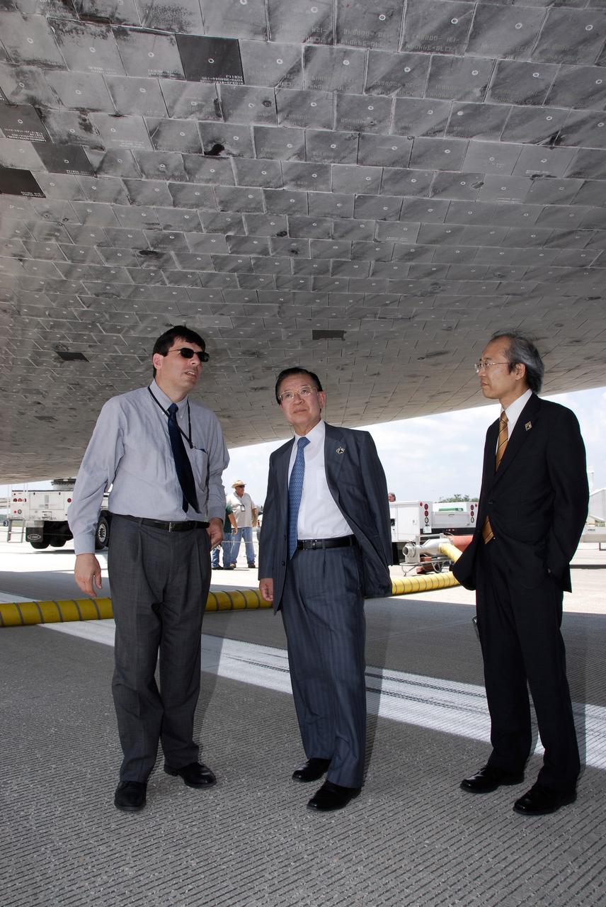 CAPE CANAVERAL, Fla. – After space shuttle Discovery's landing on Runway 15 at NASA's Kennedy Space Center, NASA Associate Administrator Chris Scolese (left) joins the Japan Aerospace Exploration Agency's Vice President Kaoru Mamiya (center) and Director of Program Management and Integration Yuichi Yamaura to look at the orbiter's underside. Discovery's landing ended the STS-124 mission, a 14-day flight to the International Space Station. The main landing gear touched down at 11:15:19 a.m. EDT. The nose landing gear touched down at 11:15:30 a.m. and wheel stop was at 11:16:19 a.m. The mission completed 5.7 million miles. The STS-124 mission delivered the Japan Aerospace Exploration Agency's large Japanese Pressurized Module and its remote manipulator system to the space station. Photo credit: NASA/Kim Shiflett
