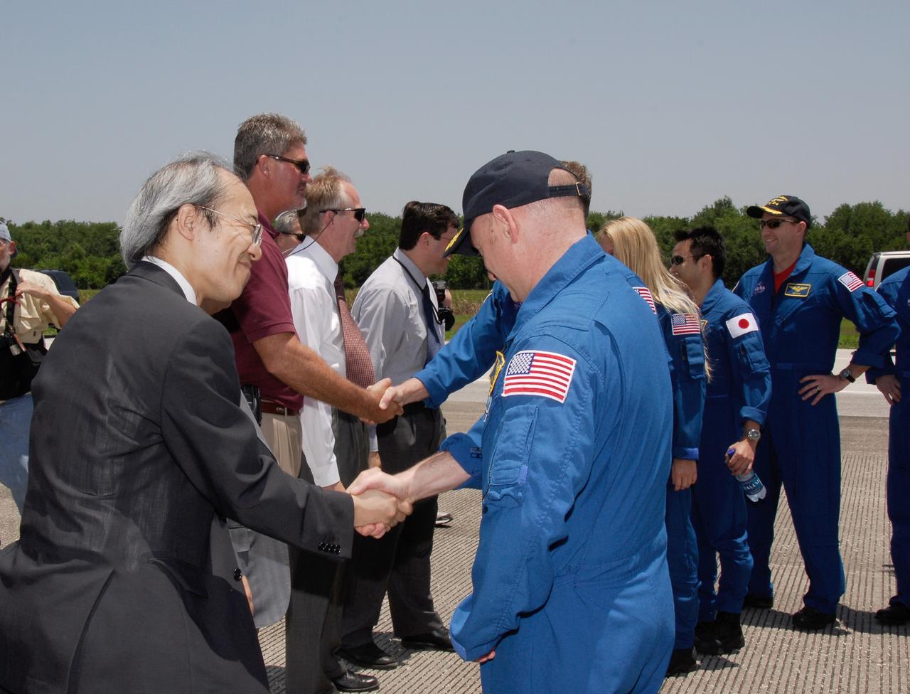 CAPE CANAVERAL, Fla. – After the successful STS-124 mission and landing on Runway 15 at NASA's Kennedy Space Center, Commander Mark Kelly (left) is greeted by the Japan Aerospace Exploration Agency's Director of Program Management and Integration Yuichi Yamaura. Other VIPs greeting the crew are Kennedy Space Center Director Bill Parsons, Associate Administrator for Space Operations Bill Gerstenmaier and NASA Associate Administrator Chris Scolese. The other crew members are Mission Specialists Karen Nyberg and Akihiko Hoshide and Pilot Ken Ham. Space shuttle Discovery's main landing gear touched down at 11:15:19 a.m. EDT on Runway 15. The nose landing gear touched down at 11:15:30 a.m. and wheel stop was at 11:16:19 a.m. The mission completed 5.7 million miles. The STS-124 mission delivered the Japan Aerospace Exploration Agency's large Japanese Pressurized Module and its remote manipulator system to the space station. Photo credit: NASA/Kim Shiflett