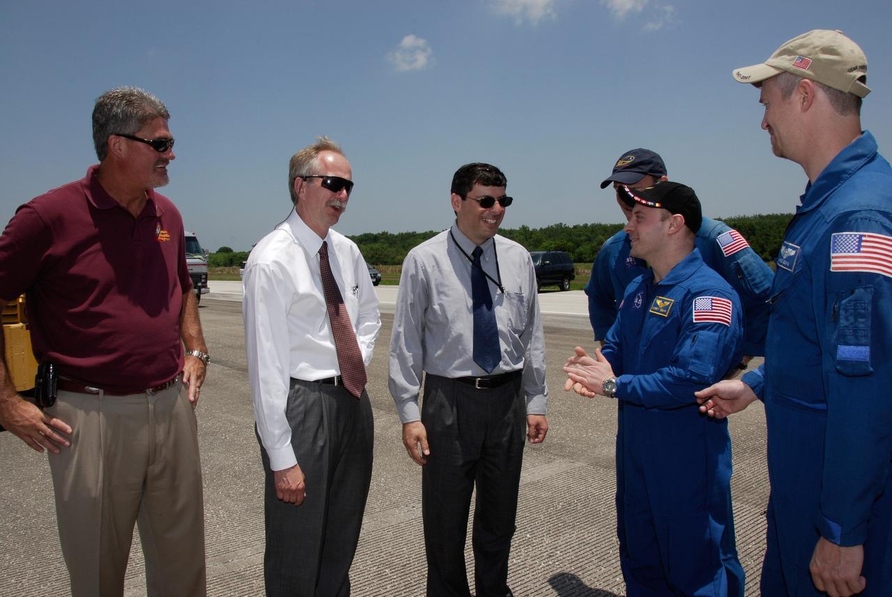 CAPE CANAVERAL, Fla.  –  After their successful STS-124 mission and landing on Runway 15 at NASA's Kennedy Space Center, crew members are greeted by NASA VIPs.  From left, Kennedy Space Center Director Bill Parsons, NASA Associate Administrator for Space Operations Bill Gerstenmaier and NASA Associate Administrator Chris Scolese talk with Garrett Reisman (center, right).  Reisman returned with the STS-124 crew after spending 95 days on the International Space Station as part of the Expedition 17 crew, ending a 14-day mission to the International Space Station.   Space shuttle Discovery's main landing gear touched down at 11:15:19 a.m. EDT on Runway 15. The nose landing gear touched down at 11:15:30 a.m. and wheel stop was at 11:16:19 a.m. The mission completed 5.7 million miles. The STS-124 mission delivered the Japan Aerospace Exploration Agency's large Japanese Pressurized Module and its remote manipulator system to the space station.   Photo credit: NASA/Kim Shiflett