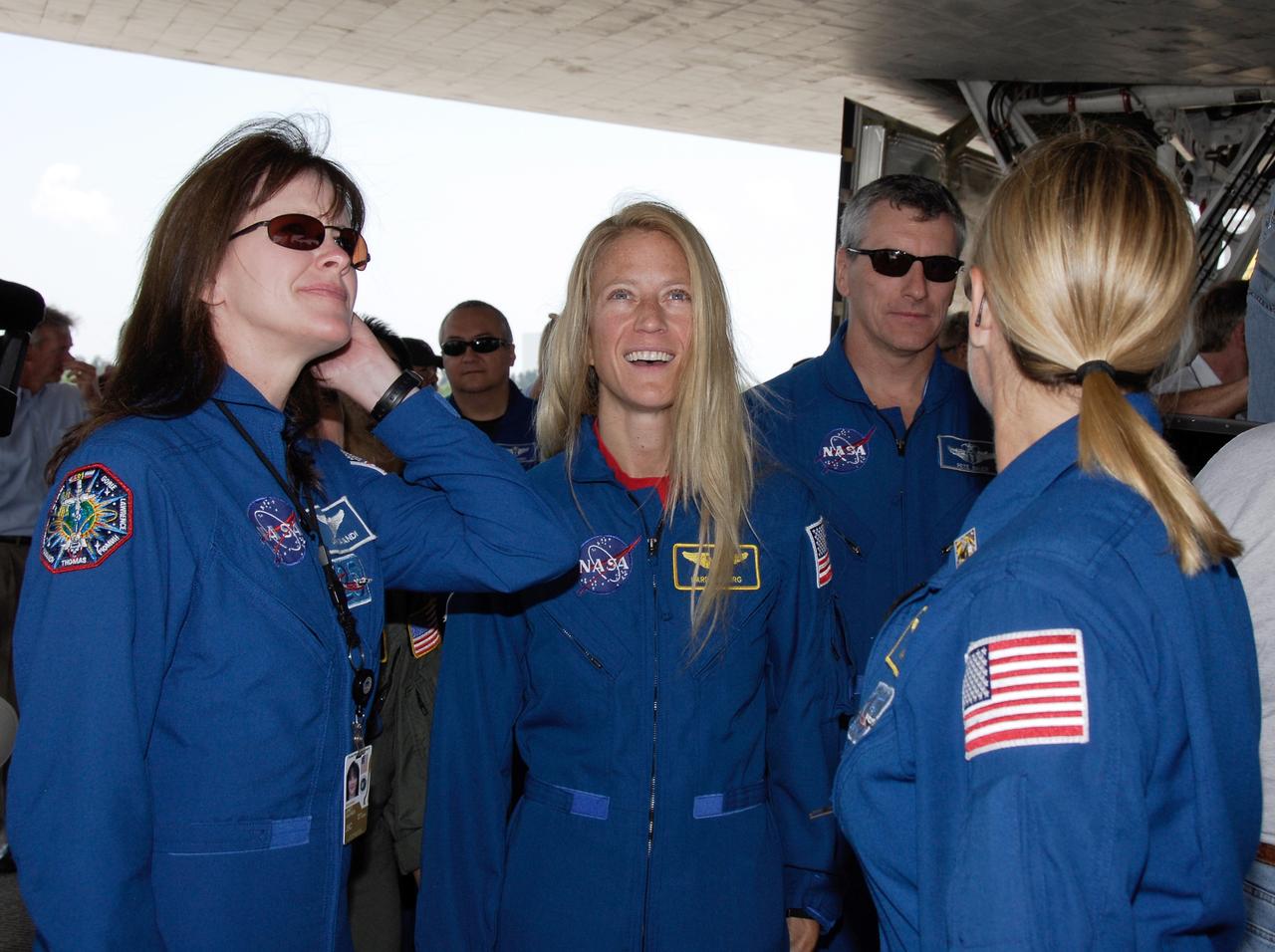 CAPE CANAVERAL, Fla. – STS-124 Mission Specialist Karen Nyberg (center) looks at the underside of space shuttle Discovery during the traditional walk-around after landing. At left is astronaut Janet Kavandi. The STS-124 mission ended with ttle Discovery's landing on Runway 15 at NASA's Kennedy Space Center, ending a 14-day mission to the International Space Station. Discovery's main landing gear touched down at 11:15:19 a.m. EDT on Runway 15. The nose landing gear touched down at 11:15:30 a.m. and wheel stop was at 11:16:19 a.m. The mission completed 5.7 million miles. The STS-124 mission delivered the Japan Aerospace Exploration Agency's large Japanese Pressurized Module and its remote manipulator system to the space station. Photo credit: NASA/Kim Shiflett