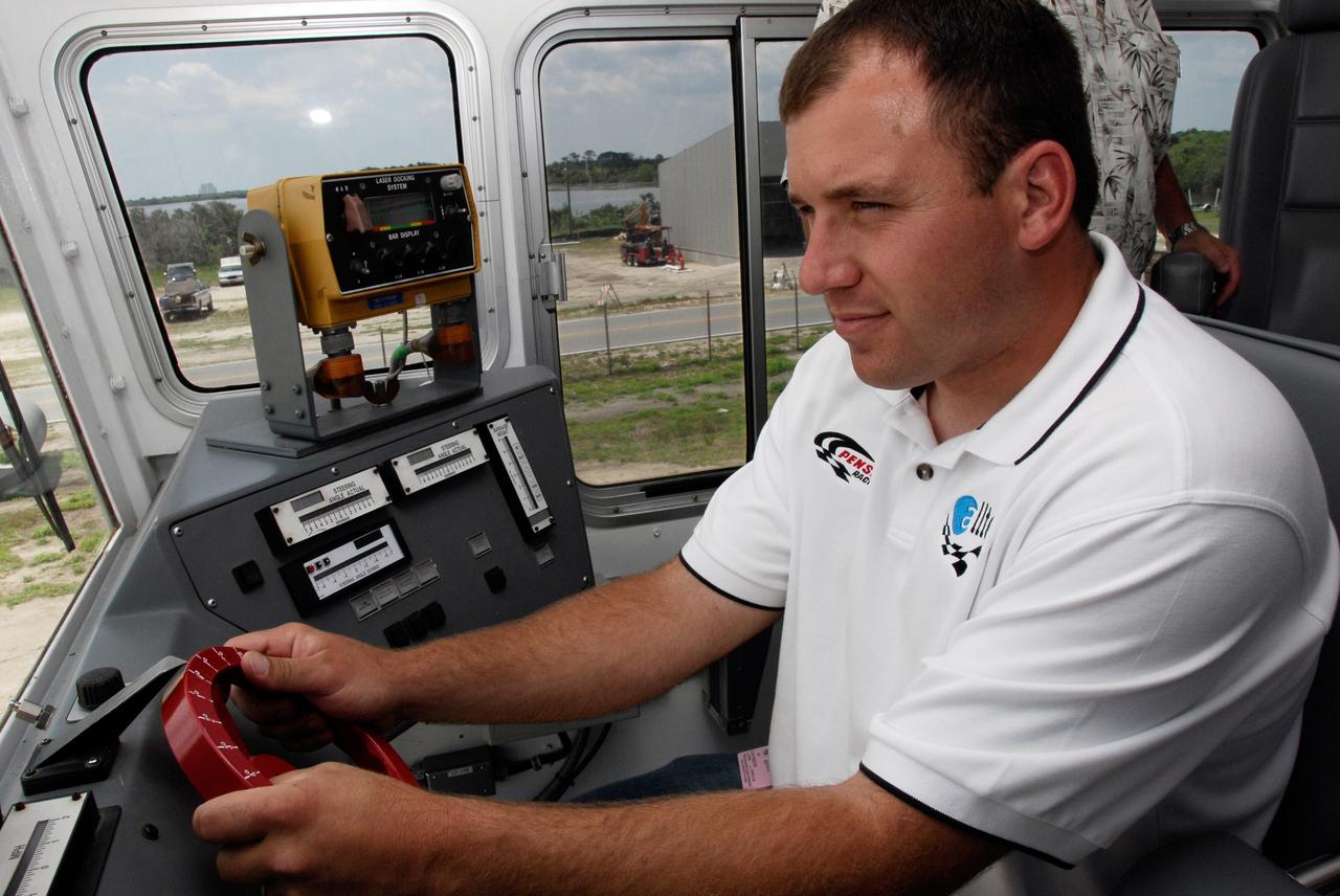 CAPE CANAVERAL, Fla.  –   2008 Daytona 500 winner Ryan Newman sits behind the wheel of a crawler-transporter at NASA's Kennedy Space Center.  Unlike his winning race car, the maximum speed of a crawler is 2 mph unloaded. Newman is visiting Kennedy in honor of NASA's 50th anniversary and the 50th running of NASCAR's Daytona 500 in February. NASA presented Newman two green racing flags that were flown last February aboard space shuttle Atlantis' STS-122 mission to the International Space Station. One flag was given to Newman, the second was presented to Daytona 500 Experience General Manager Kim Isemann. A third flag that was flown will be kept by NASA for public display.  The connection between NASA and Daytona's International Speedway extends beyond their close proximity to one another. During recent years, technology developed for the space program has found many uses on Earth, including helping NASCAR drivers stay safe and increase performance.  Photo credit: NASA/Kim Shiflett