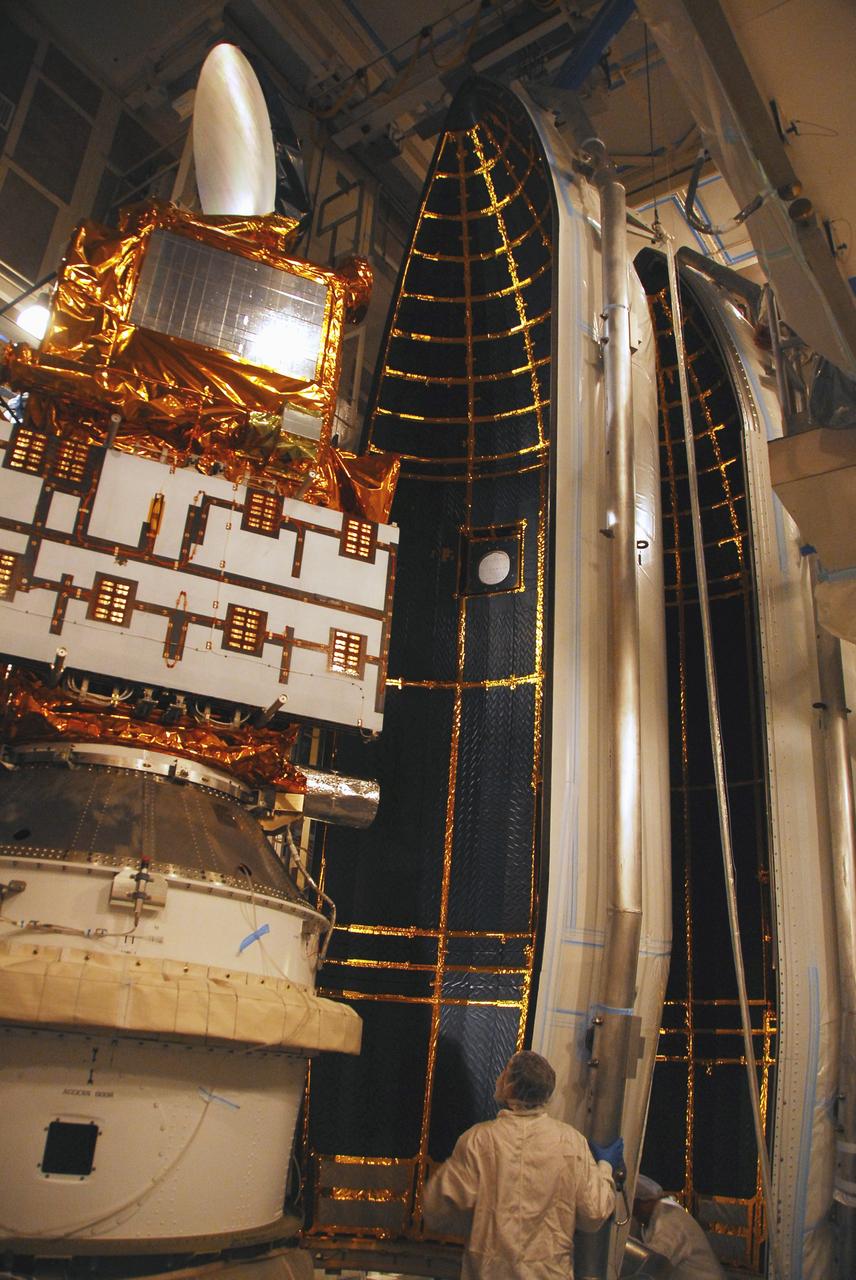 VANDENBERG AIR FORCE BASE, Calif. –   In the mobile service tower on Space Launch Complex 2, the first half of the fairing (at right) is moved closer toward the Ocean Surface Topography Mission, or OSTM/Jason 2, spacecraft for encapsulation.  The fairing is a molded structure that fits flush with the outside surface of the Delta II upper stage booster and forms an aerodynamically smooth nose cone, protecting the spacecraft during launch and ascent. The launch of the OSTM/Jason-2 is scheduled for June 20 from Vandenberg Air Force Base. The launch window extends from 12:46 a.m. to 12:55 a.m. PDT. The satellite will be placed in an 830-mile-high orbit at an inclination of 66 degrees after separating from the Delta II 55 minutes after liftoff.  The five primary science instruments of the Ocean Surface Topography Mission aboard the Jason 2 spacecraft are dedicated to measuring the height of the ocean surface. These measurements will be used to evaluate and forecast climate changes and improve weather forecasting. The results also are expected to help forecasters better predict hurricane intensity.