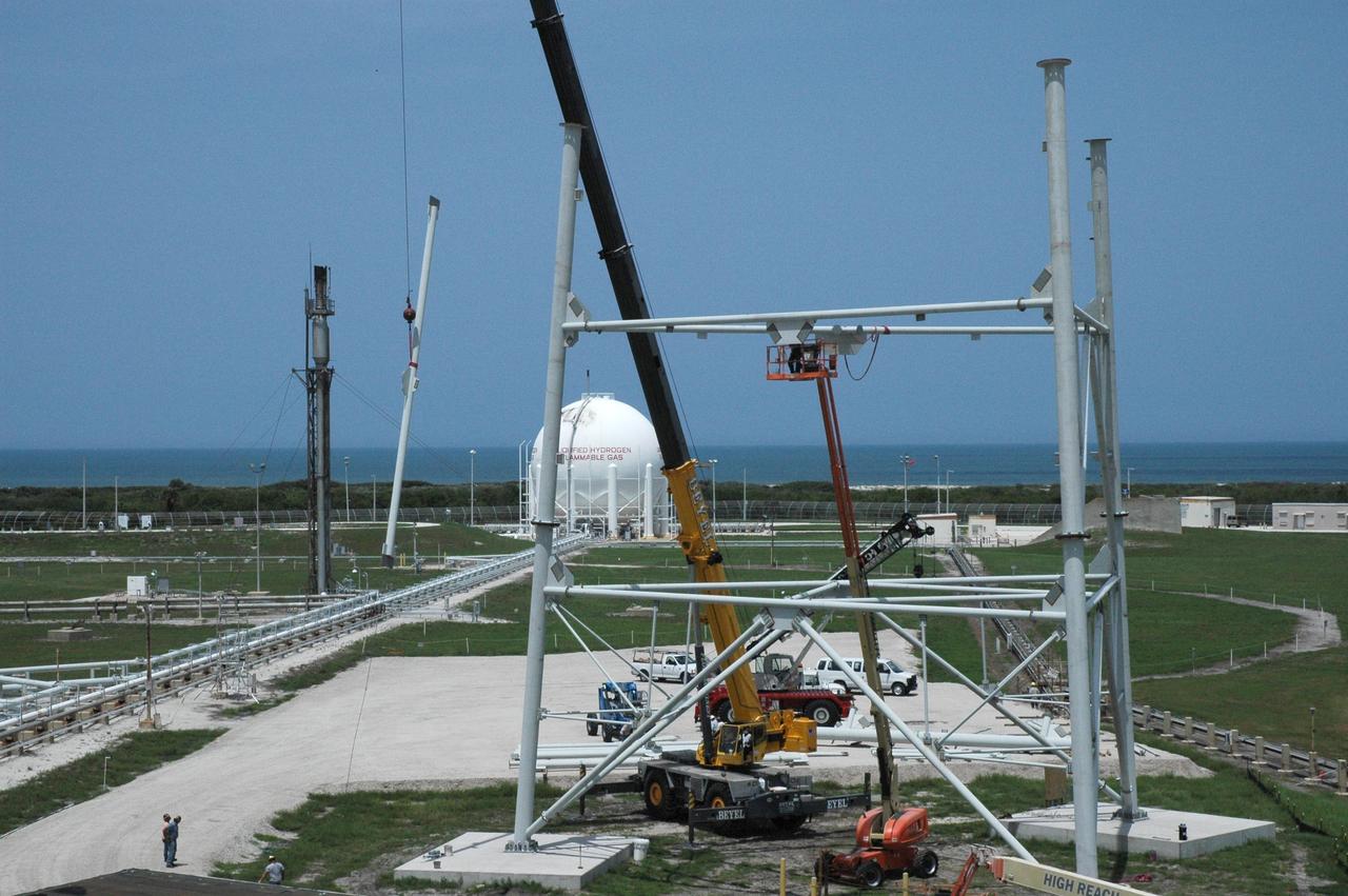 CAPE CANAVERAL, Fla. – With the backdrop of a blue sky and the blue Atlantic Ocean, workers are constructing the lightning towers on Launch Pad 39B at NASA's Kennedy Space Center. In the background, at left, is the liquid hydrogen tank that helps fuel a space shuttle for launch. Each of the three new lightning towers will be 500 feet tall with an additional 100-foot fiberglass mast atop supporting a wire centenary system. This improved lightning protection system also allows for the taller height of the Ares I compared to the space shuttle. Pad B will be the site of the first Ares vehicle launch, including Ares I-X which is scheduled for April 2009, as part of the Constellation Program. Photo credit: NASA/Jim Grossmann