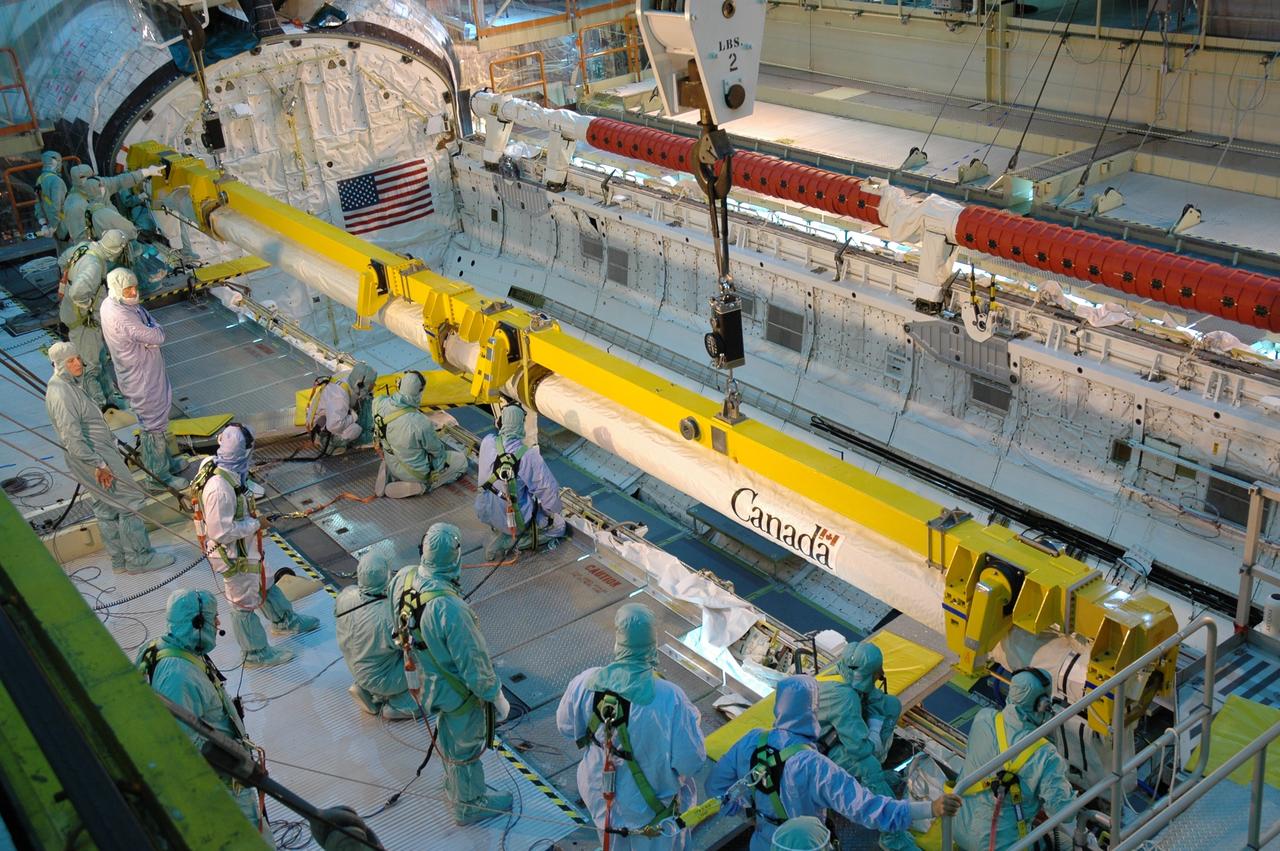 CAPE CANAVERAL, Fla. – In the Orbiter Processing Facility bay 3, workers ensure space shuttle Discovery's robotic arm is placed correctly for installation in the payload bay. Scheduled to launch on the STS-119 mission, Discovery will carry the S6 truss segment to complete the 361-foot-long backbone of the International Space Station. The truss includes the fourth pair of solar array wings and electronics that convert sunlight to power for the orbiting laboratory. A launch date has not yet been determined. Photo credit: NASA/Jim Grossmann