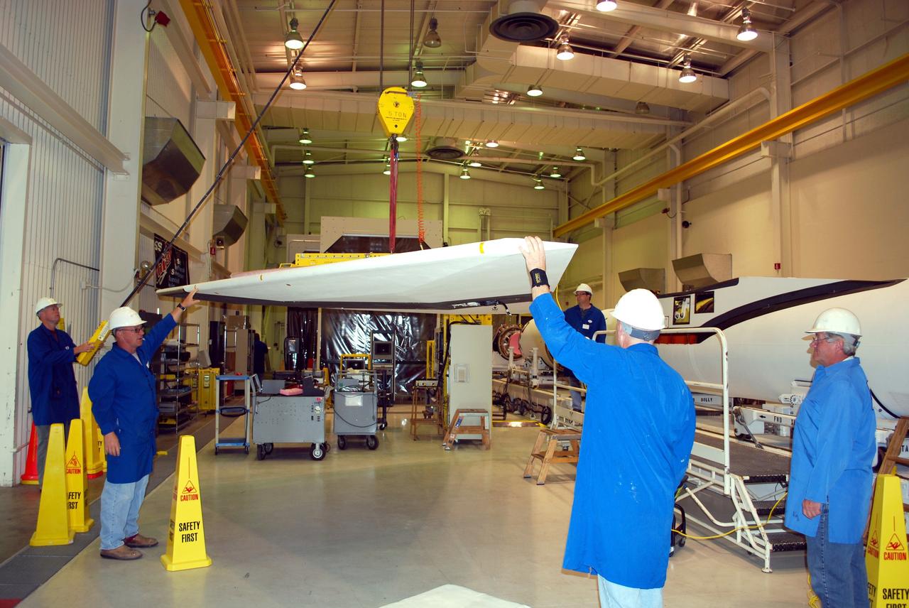 VANDENBERG AIR FORCE BASE, Calif. -- Workers in Building 1555 at Vandenberg AFB help guide the wing toward the Pegasus rocket for installation. The Pegasus will launch NASA's Interstellar Boundary Explorer Mission, or IBEX, satellite from Kwajalein Island in the Marshall Islands, South Pacific. IBEX will make the first map of the boundary between the solar system and interstellar space. IBEX is the first mission designed to detect the edge of the solar system. As the solar wind from the sun flows out beyond Pluto, it collides with the material between the stars, forming a shock front. IBEX contains two neutral atom imagers designed to detect particles from the termination shock at the boundary between the solar system and interstellar space. IBEX also will study galactic cosmic rays, energetic particles from beyond the solar system that pose a health and safety hazard for humans exploring beyond Earth orbit. IBEX will make these observations from a highly elliptical orbit that takes it beyond the interference of the Earth's magnetosphere. IBEX is targeted for launch in September 2008. Photo credit: NASA/ Randy Beaudoin