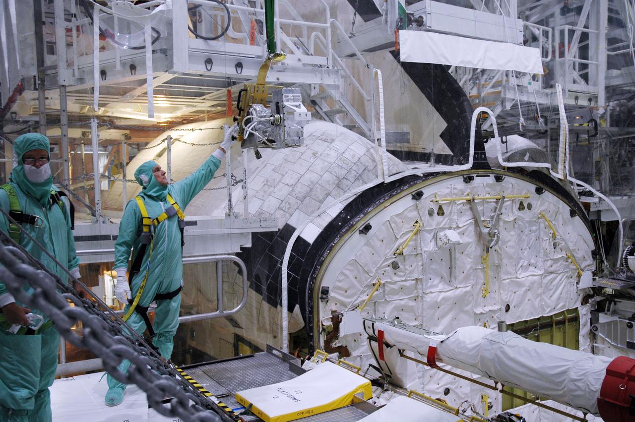 CAPE CANAVERAL, Fla. – In the Orbiter Processing Facility bay 2 at NASA's Kennedy Space Center, a worker reaches up to the camera pack to be installed on space shuttle Endeavour's orbiter boom sensor system. The scheduled launch vehicle for the STS-126 missions, Endeavour will deliver a multi-purpose logistics module to the International Space Station. Launch is targeted for Nov. 10. Endeavour is also the backup shuttle, if needed for rescue, for the STS-125 mission in October that will make repairs on NASA's Hubble Space Telescope. For that purpose, it is designated STS-400. Photo credit: NASA/Jim Grossmann