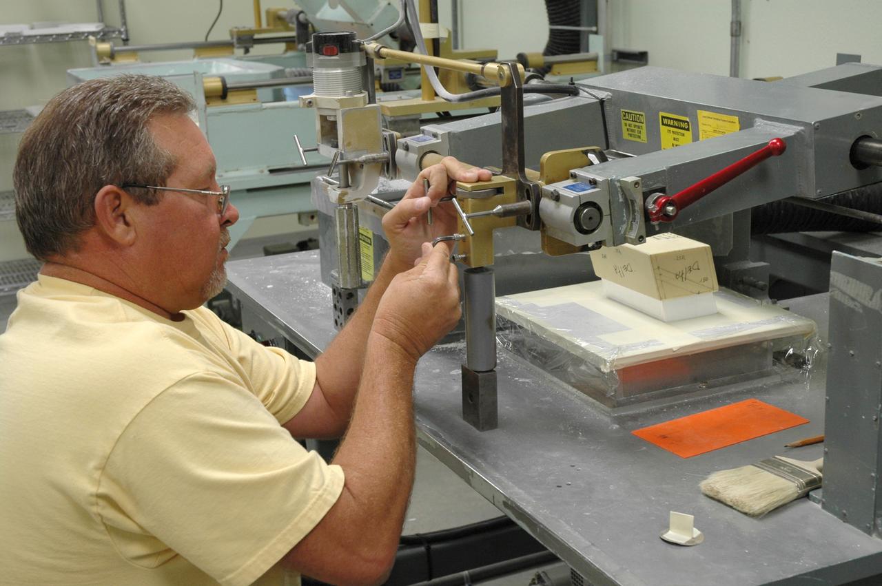 CAPE CANAVERAL, Fla. –  In the Tile Shop at NASA's Kennedy Space Center, a United Space Alliance machinist, Tony Rollins, is setting up the tracer mill to machine the Boeing Rigid Insulation-18, or BRI-18, tile.  BRI-18 is the strongest material used for thermal insulation on the orbiters and, when coated to produce toughened unipiece fibrous insulation, provides a tile with extremely high-impact resistance.  It is replacing tiles on areas of the vehicle where impact risk is high.  These areas include the landing gear doors, the wing leading edge and the external tank doors.  Photo credit: NASA/Jim Grossmann