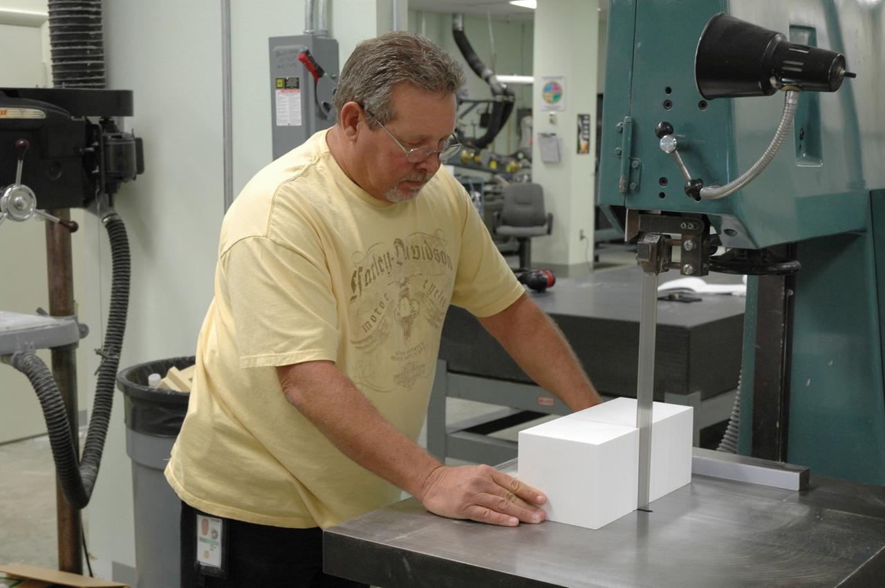 CAPE CANAVERAL, Fla. –  In the Tile Shop at NASA's Kennedy Space Center, a United Space Alliance technician cuts a block of Boeing Rigid Insulation-18, or BRI-18, tile.  BRI-18 is the strongest material used for thermal insulation on the orbiters and, when coated to produce toughened unipiece fibrous insulation, provides a tile with extremely high-impact resistance.  It is replacing tiles on areas of the vehicle where impact risk is high.  These areas include the landing gear doors, the wing leading edge and the external tank doors.  Photo credit: NASA/Jim Grossmann
