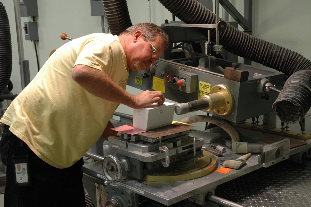 CAPE CANAVERAL, Fla. –    In the Tile Shop at NASA's Kennedy Space Center, a United Space Alliance technician checks the Boeing Rigid Insulation-18, or BRI-18, tile he cut.  BRI-18 is the strongest material used for thermal insulation on the orbiters and, when coated to produce toughened unipiece fibrous insulation, provides a tile with extremely high-impact resistance.  It is replacing tiles on areas of the vehicle where impact risk is high.  These areas include the landing gear doors, the wing leading edge and the external tank doors.  Photo credit: NASA/Jim Grossmann