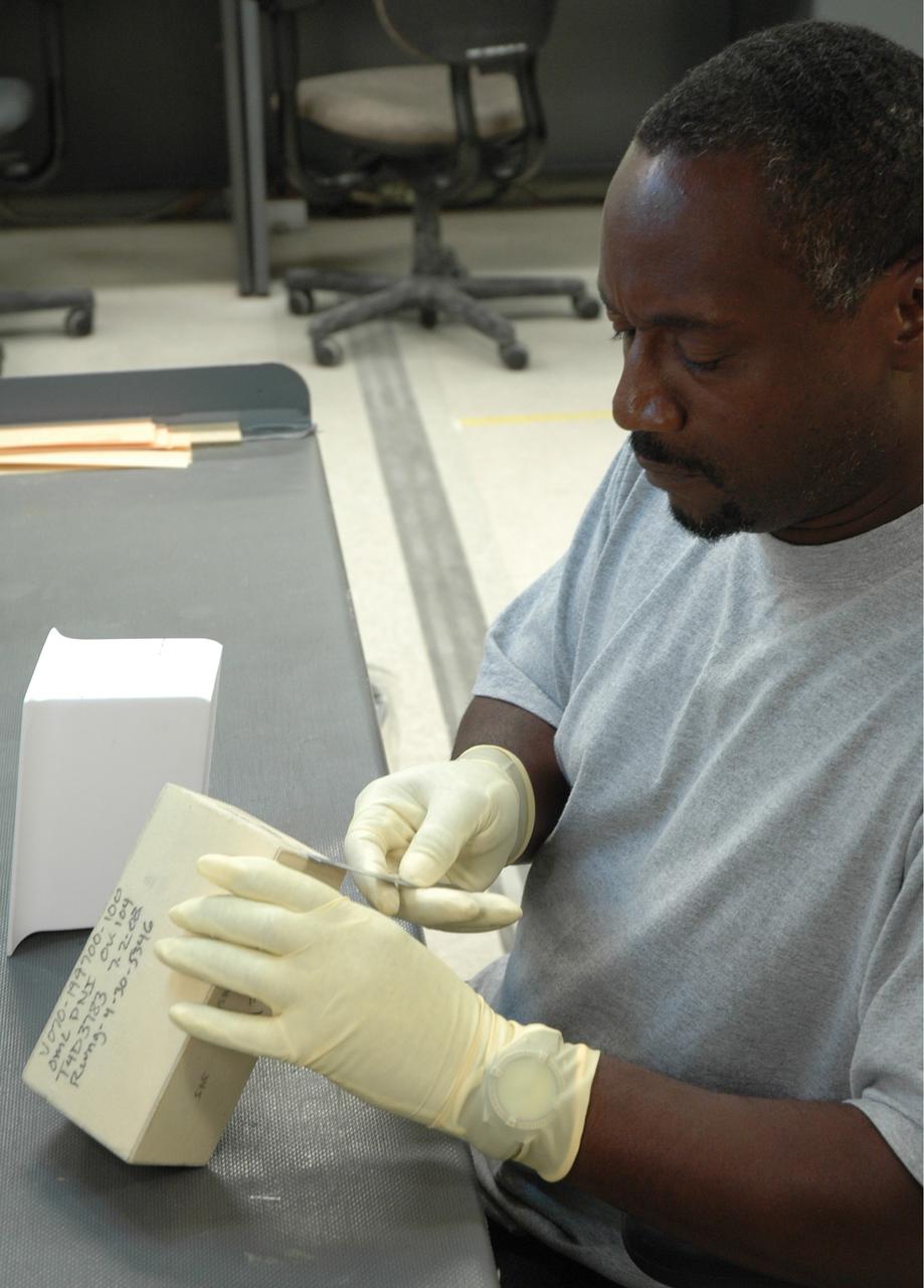 CAPE CANAVERAL, Fla. –  In the Tile Shop at NASA's Kennedy Space Center, a United Space Alliance technician checks a Boeing Rigid Insulation-18, or BRI-18, tile.  BRI-18 is the strongest material used for thermal insulation on the orbiters and, when coated to produce toughened unipiece fibrous insulation, provides a tile with extremely high-impact resistance.  It is replacing tiles on areas of the vehicle where impact risk is high.  These areas include the landing gear doors, the wing leading edge and the external tank doors.  Photo credit: NASA/Jim Grossmann