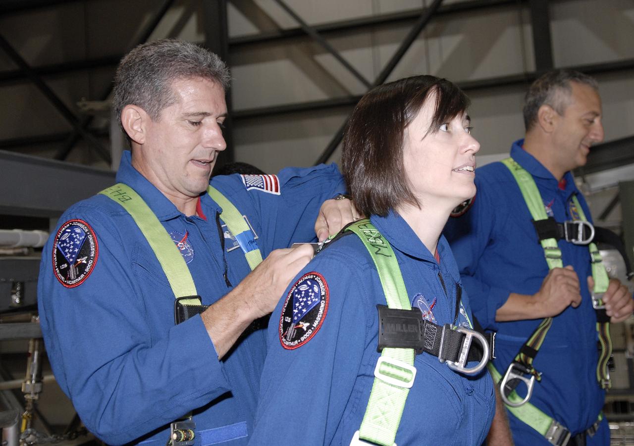 CAPE CANAVERAL, Fla. – In the Orbiter Processing Facility at NASA's Kennedy Space Center, STS-125 Mission Specialist Michael Good helps Mission Specialist Megan McArthur put on a safety harness to look inside space shuttle Atlantis' payload bay. Mission Specialist Mike Massimino also is shown. Crew members are at Kennedy for a crew equipment interface test, which provides hands-on experience with hardware and equipment for their mission. Atlantis is targeted to launch on the STS-125 Hubble Servicing Mission 4 on Oct. 8. Photo credit: NASA/Kim Shiflett