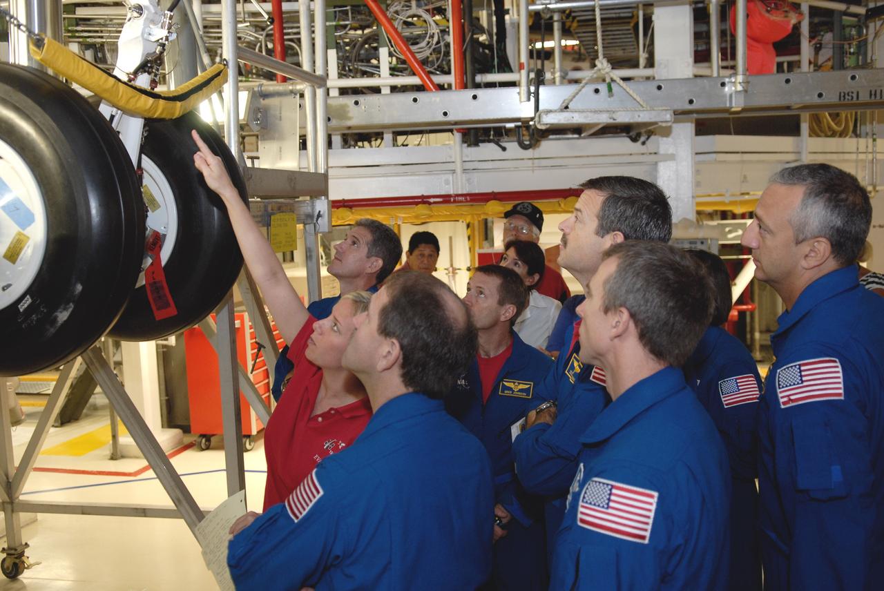 CAPE CANAVERAL, Fla. – In the Orbiter Processing Facility at NASA's Kennedy Space Center, a technician points to the landing gear on the underside of space shuttle Atlantis as STS-125 crew members look on. In the foreground are Mission Specialists John Grunsfeld and Andrew Feustel. Behind them, from left, are Mission Specialist Michael Good, Pilot Gregory C. Johnson, Commander Scott Altman and Mission Specialists Megan McArthur (face hidden) and Mike Massimino. Crew members are at Kennedy for a crew equipment interface test, which provides hands-on experience with hardware and equipment for their mission. Atlantis is targeted to launch on the STS-125 Hubble Servicing Mission 4 on Oct. 8. Photo credit: NASA/Kim Shiflett