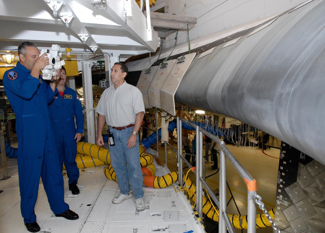 CAPE CANAVERAL, Fla. –  In the Orbiter Processing Facility at NASA's Kennedy Space Center, STS-125 Mission Specialist Mike Massimino focuses on the wing of space shuttle Atlantis with a camera to be used on the mission as Mission Specialist John Grunsfeld observes.  The crew is at Kennedy for a crew equipment interface test, which provides hands-on experience with hardware and equipment for the mission. Atlantis is targeted to launch on the STS-125 Hubble Servicing Mission 4 on Oct. 8.  Photo credit: NASA/Kim Shiflett