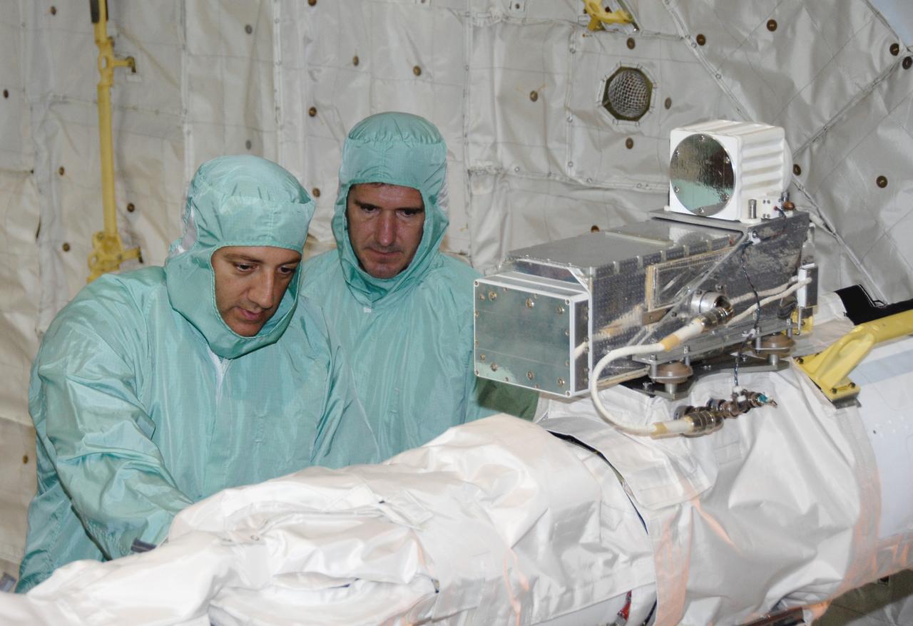 CAPE CANAVERAL, Fla. – In the Orbiter Processing Facility at NASA's Kennedy Space Center, STS-125 Mission Specialists Mike Massimino (left) and Michael Good (right) check out the orbiter boom sensor system and the attached camera in space shuttle Atlantis' payload bay. Equipment familiarization is part of the crew equipment interface test, which provides hands-on experience with hardware and equipment for the mission. Atlantis is targeted to launch Oct. 8 on the STS-125 mission to service the Hubble Space Telescope. The mission crew will perform history-making, on-orbit “surgery” on two important science instruments aboard the telescope. After capturing the telescope, two teams of spacewalking astronauts will perform the repairs during five planned spacewalks. Photo credit: NASA/Kim Shiflett