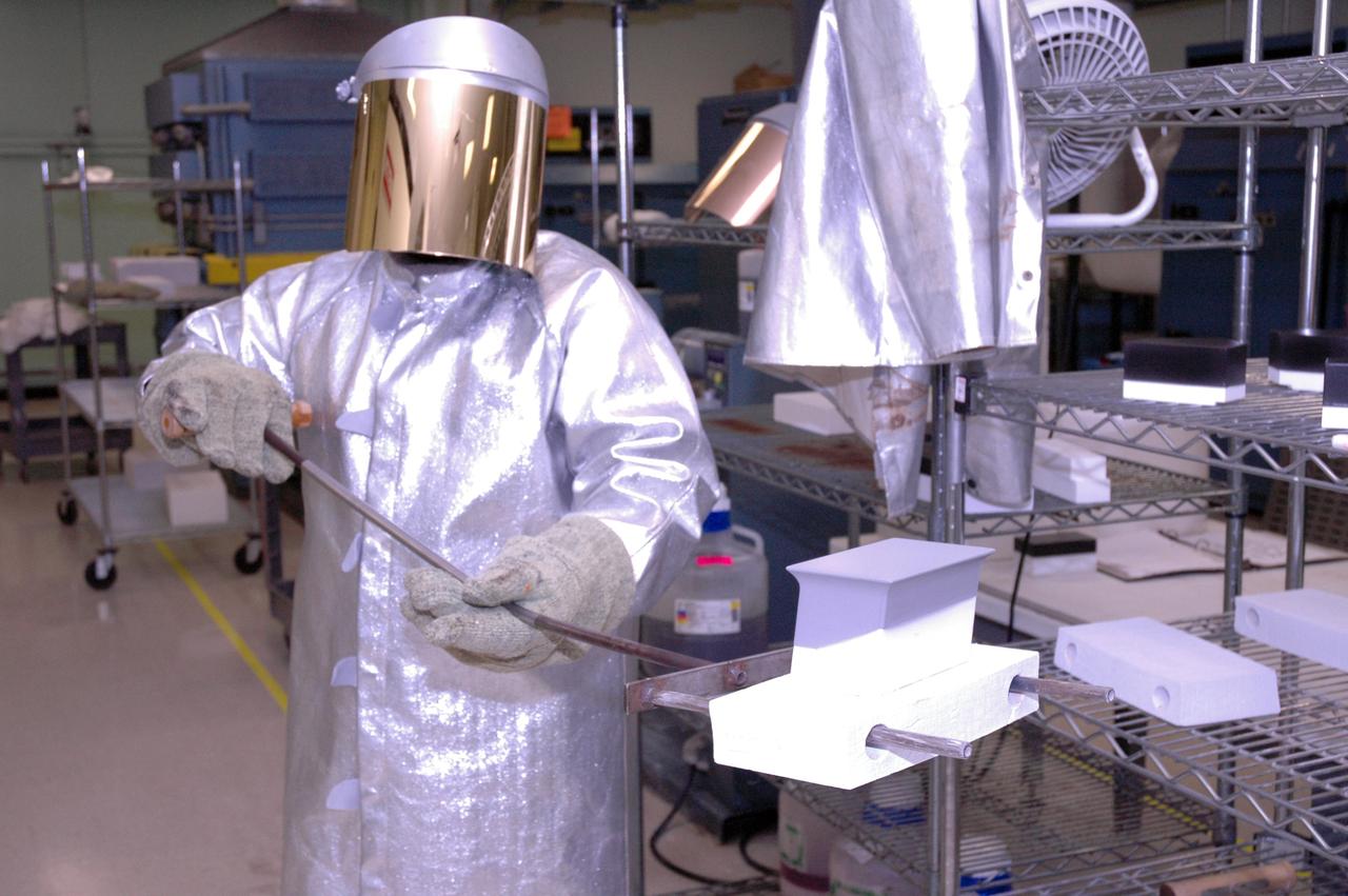 CAPE CANAVERAL, Fla. – In the tile shop at NASA's Kennedy Space Center, a worker is ready to place a Boeing Replacement Insulation 18, or BRI-18, tile in the oven. The tile will be baked at 2,200 degrees Fahrenheit to cure the ceramic coating, part of the process to prepare the tiles for installation on space shuttles. BRI-18 is the strongest material used for thermal insulation on the orbiters and, when coated to produce toughened unipiece fibrous insulation, provides a tile with extremely high-impact resistance. It is replacing other tiles on areas of the vehicle where impact risk is high, such as the landing gear doors, the wing leading edge and the external tank doors. Photo credit: NASA/Jim Grossmann