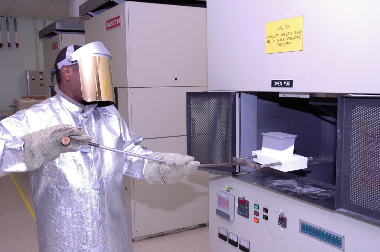 CAPE CANAVERAL, Fla. – In the tile shop at NASA's Kennedy Space Center, a worker places a Boeing Replacement Insulation 18, or BRI-18, tile in the oven. The tile will be baked at 2,200 degrees Fahrenheit to cure the ceramic coating, part of the process to prepare the tiles for installation on space shuttles. BRI-18 is the strongest material used for thermal insulation on the orbiters and, when coated to produce toughened unipiece fibrous insulation, provides a tile with extremely high-impact resistance. It is replacing other tiles on areas of the vehicle where impact risk is high, such as the landing gear doors, the wing leading edge and the external tank doors. Photo credit: NASA/Jim Grossmann