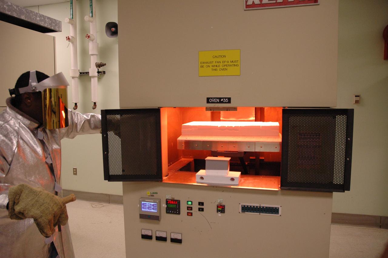 CAPE CANAVERAL, Fla. – In the tile shop at NASA's Kennedy Space Center, a worker reaches for the door to close the oven with the Boeing Replacement Insulation 18, or BRI-18, tile inside. The tile will be baked at 2,200 degrees Fahrenheit to cure the ceramic coating, part of the process to prepare the tiles for installation on space shuttles. BRI-18 is the strongest material used for thermal insulation on the orbiters and, when coated to produce toughened unipiece fibrous insulation, provides a tile with extremely high-impact resistance. It is replacing other tiles on areas of the vehicle where impact risk is high, such as the landing gear doors, the wing leading edge and the external tank doors. Photo credit: NASA/Jim Grossmann