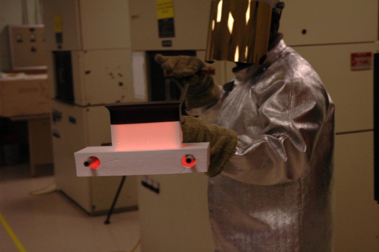 CAPE CANAVERAL, Fla. – In the tile shop at NASA's Kennedy Space Center, a worker removes a Boeing Replacement Insulation 18, or BRI-18, tile from a 2,200-degree oven. The baking is part of the process to prepare the tiles for installation on space shuttles. BRI-18 is the strongest material used for thermal insulation on the orbiters and, when coated to produce toughened unipiece fibrous insulation, provides a tile with extremely high-impact resistance. It is replacing other tiles on areas of the vehicle where impact risk is high, such as the landing gear doors, the wing leading edge and the external tank doors. Photo credit: NASA/Jim Grossmann