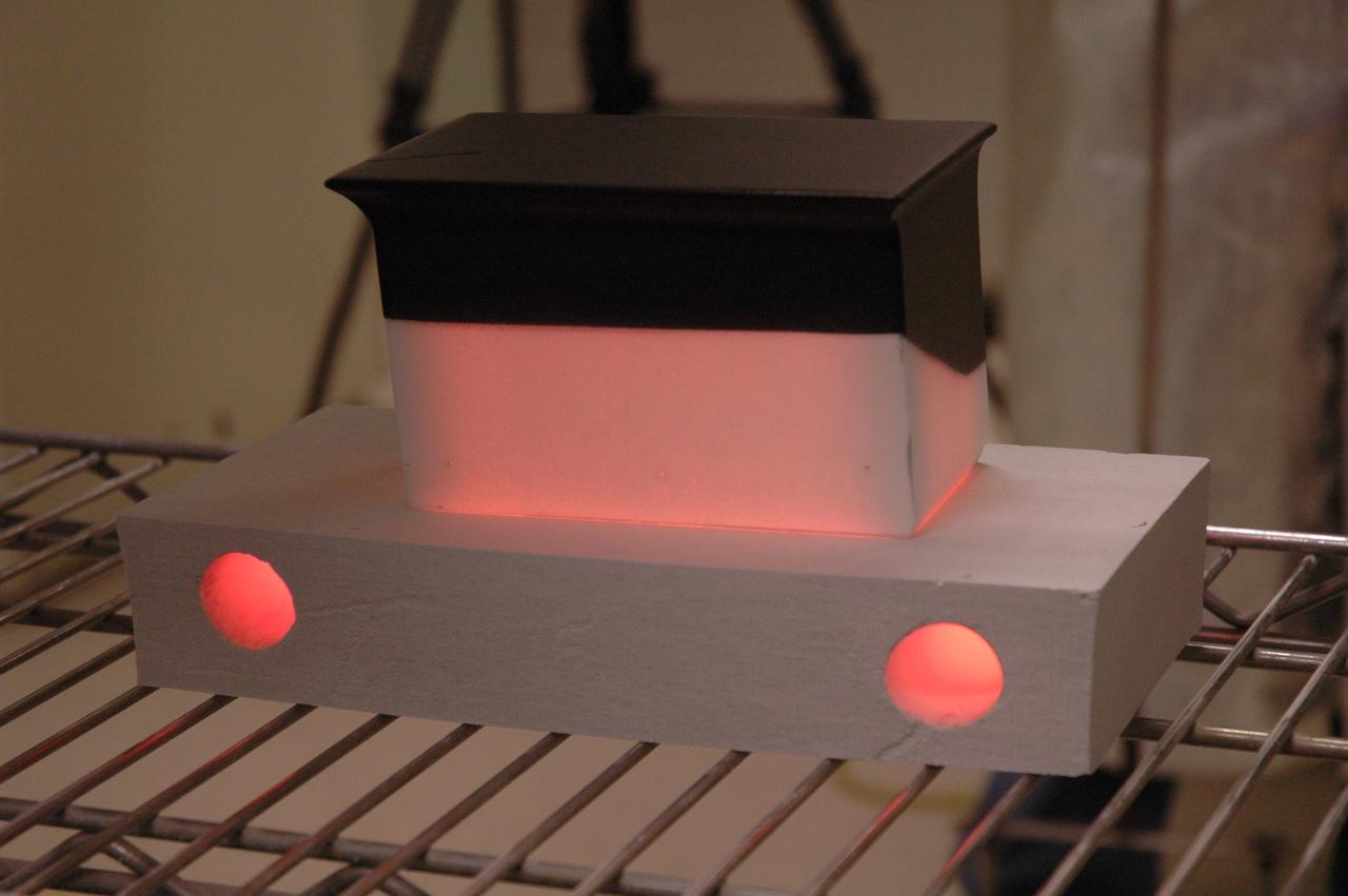 CAPE CANAVERAL, Fla. – In the tile shop at NASA's Kennedy Space Center, a Boeing Replacement Insulation 18, or BRI-18, tile still glows after being baked in a 2,200-degree oven. The baking is part of the process to prepare the tiles for installation on space shuttles. BRI-18 is the strongest material used for thermal insulation on the orbiters and, when coated to produce toughened unipiece fibrous insulation, provides a tile with extremely high-impact resistance. It is replacing other tiles on areas of the vehicle where impact risk is high, such as the landing gear doors, the wing leading edge and the external tank doors. Photo credit: NASA/Jim Grossmann