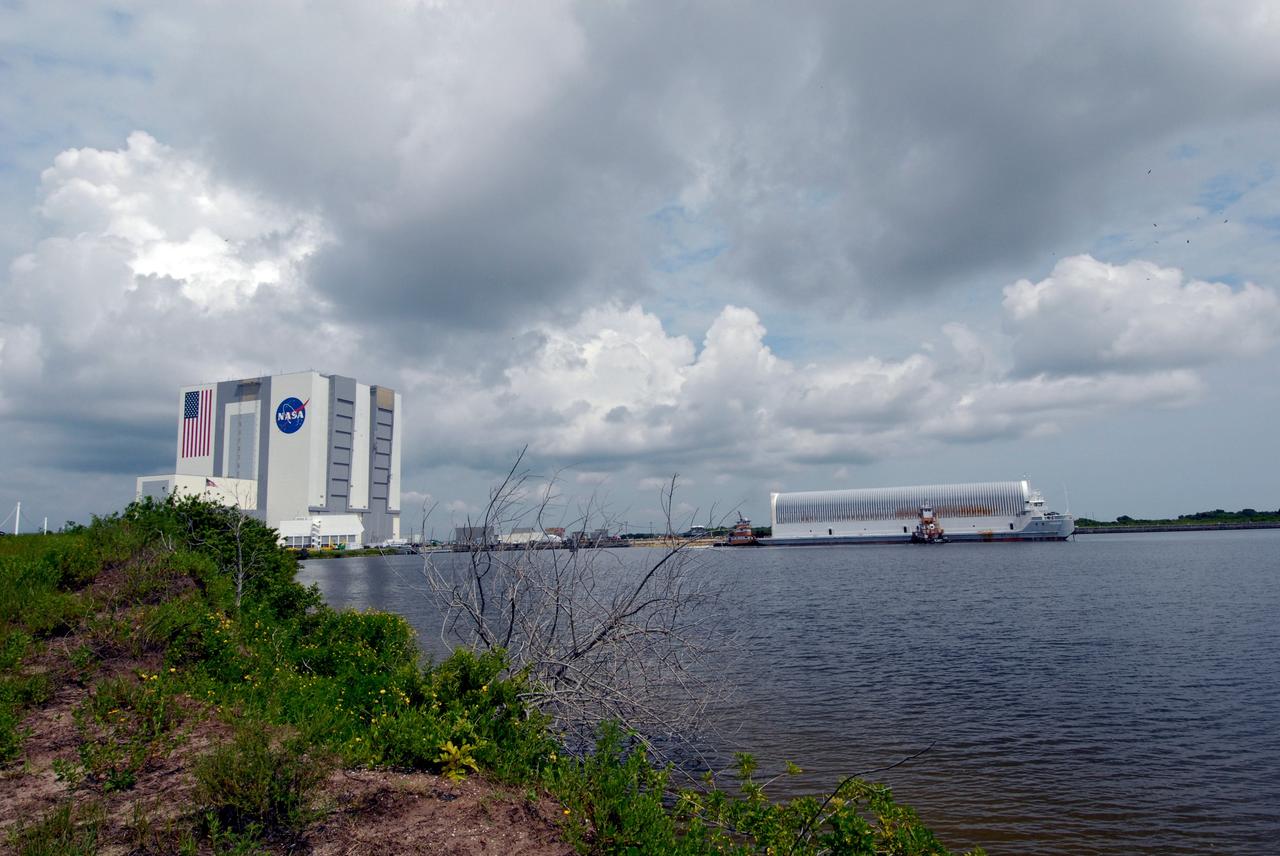 CAPE CANAVERAL, Fla. –    The external fuel tank for space shuttle Atlantis' STS-125 mission to NASA's Hubble Space Telescope is towed to the dock in the turn basin in the Launch Complex 39 Area in NASA's Kennedy Space Center.  After docking, the tank will be offloaded and moved to the Vehicle Assembly Building, at left.  Once inside the building, the tank will be raised to vertical, lifted and moved into a checkout cell.  Stacking of the tank and solid rocket boosters is planned to start Aug. 7.  Atlantis is targeted to launch Oct. 8.  Photo credit: NASA/Jack Pfaller